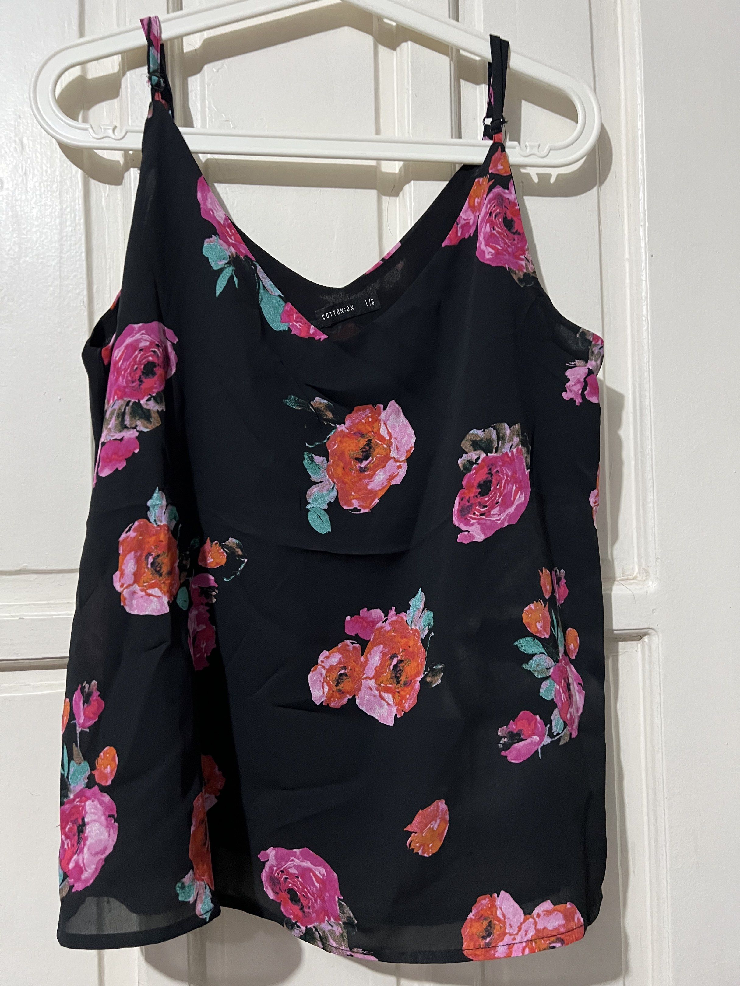 Preloved Cotton On Floral Cami Top (Category: Sleeveless) located in Binan City. Submitted by unicohijoxfudge (Listing ID 1418312638, Image 1). Description: Decluttering❤️❤️❤️ Size L 21” width x 22” length Black cami top from Cotton On with a floral print. Features adjustable straps and a V-neckline. The size is L/G. The top is made of a lightweight material, perfect for warm weather. It has a flowy silhouette and is suitable for casual wear. ✅SF