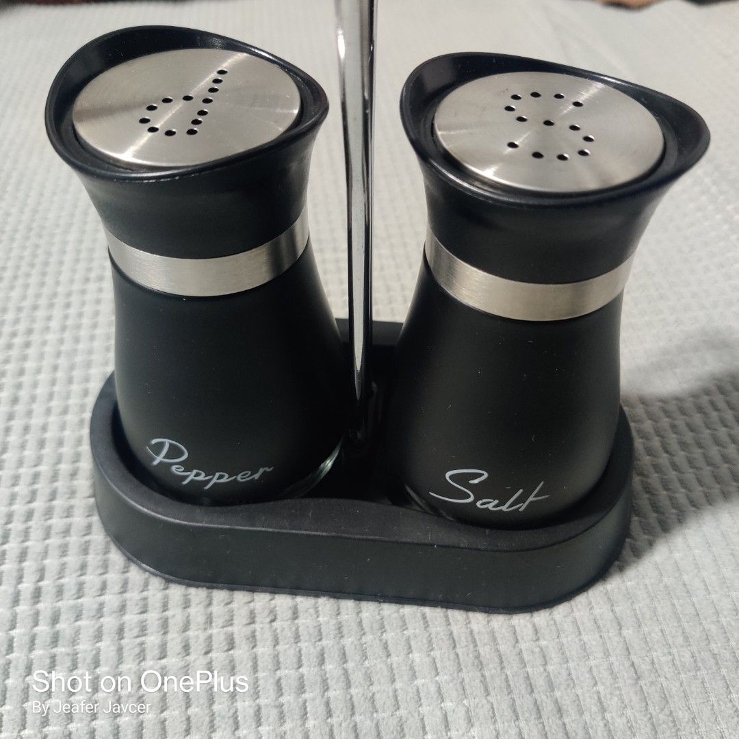 Salt and Pepper Shaker Set with Stand (Category: Other Kitchenware & Tableware) located in Baguio. Submitted by ferns_garage.0924 (Listing ID 1418346948, Image 2). Description: - Set includes salt and pepper shakers. - Sleek black design with stainless steel accents. - Clearly labeled for easy identification. - Comes with a convenient stand for organized storage. - Pepper shaker has arrow-shaped holes. - Salt shaker has circle-shaped holes. scan 