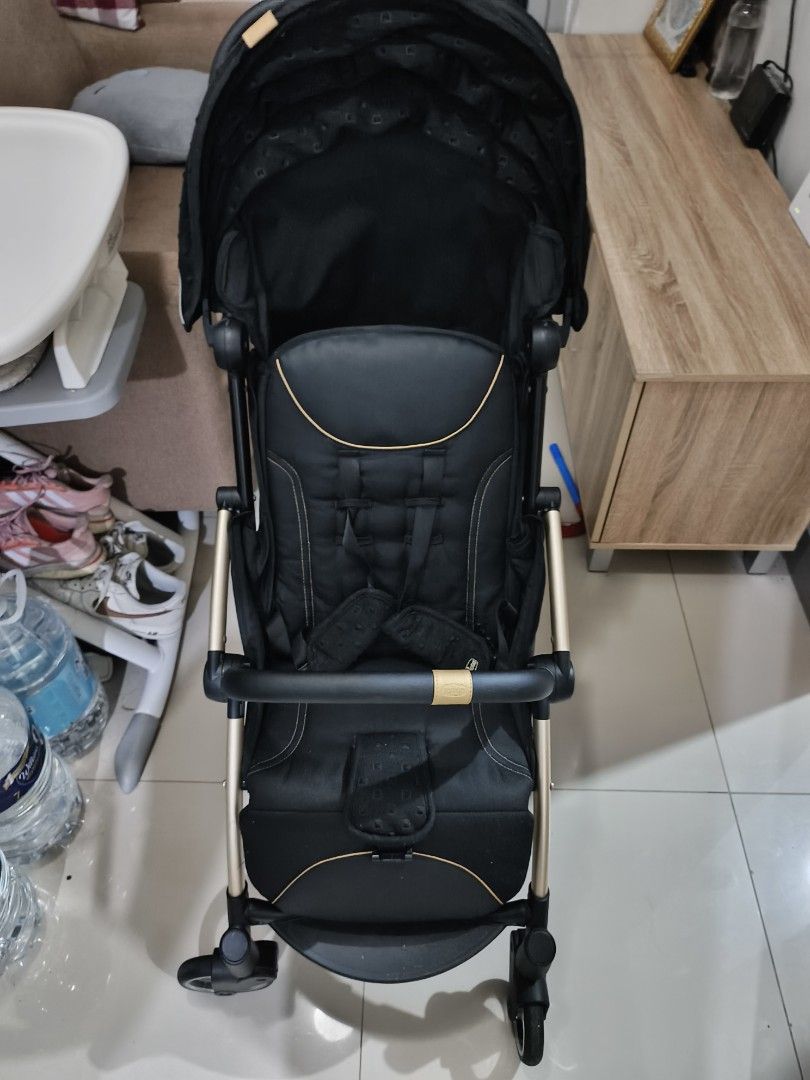Stroller (Chico brand) (Category: Strollers) located in Cainta. Submitted by inozone (Listing ID 1418321828, Image 2). Description: Stroller features a sleek black design with gold accents. It has a canopy for sun protection and a comfortable seat with a safety harness. It has a handle for pushing and wheels for smooth movement..