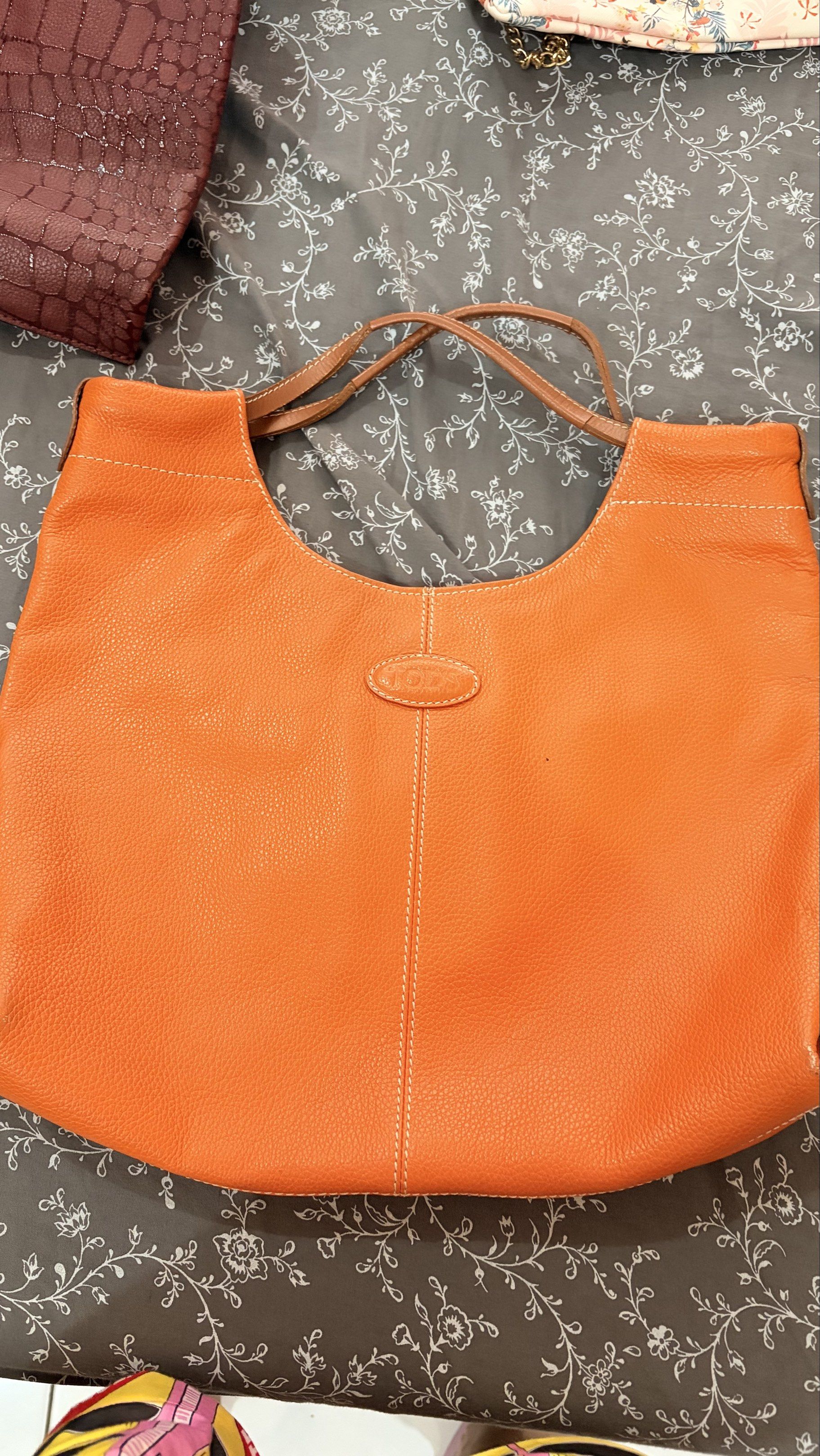Tod's Orange Leather Tote Bag (Category: Luxury Bags & Wallets) located in Tacloban City. Submitted by ysha24 (Listing ID 1418241653, Image 1). Description: - Tod's orange leather tote bag - Curved top design - Brown handles - Central seam with white stitching - Textured leather finish - Small oval Tod's logo - Vibrant orange color.
