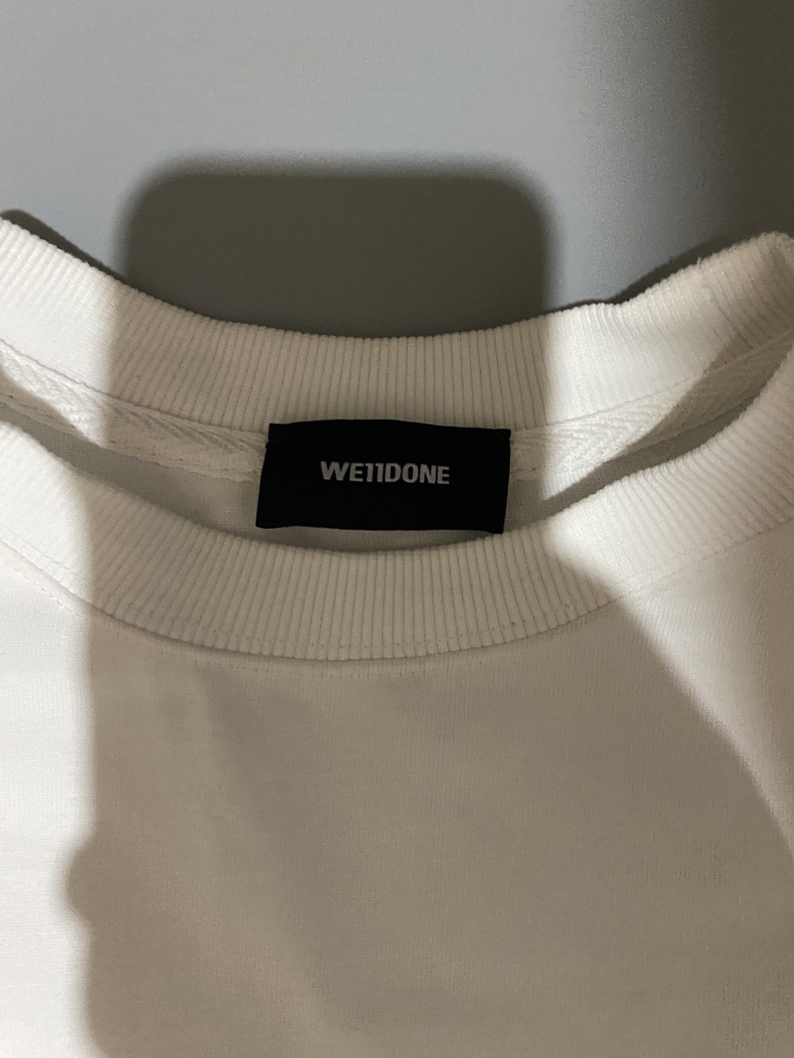 We11done White Logo T-shirt (Category: Tshirts & Polo Shirts ) located in Tagum. Submitted by thriftedjon (Listing ID 1418321826, Image 2). Description: - White We11done T-shirt - Size: XS - Features a logo print on the front - Classic crew neck and short sleeves - Includes brand tag and care instructions - Made from cotton and polyurethane - Features a QR code for authenticity verification.