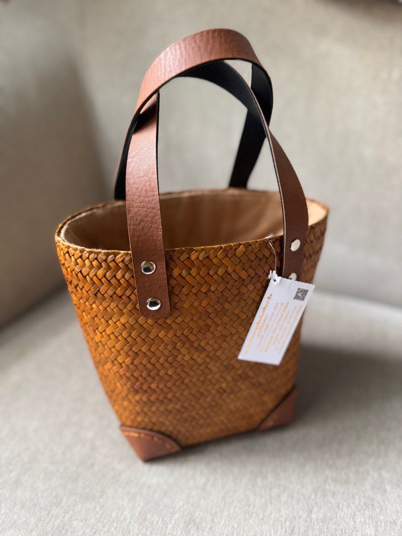 Woven Basket Bag with Leather Handles (Category: Tote Bags) located in Quezon City. Submitted by smt00 (Listing ID 1418227346, Image 1). Description: - Woven bucket bag - Brown leather handles and accents - Leather corner details - Made of natural woven material - Width: 6.5in Height: 7in - Bought in Bangkok .