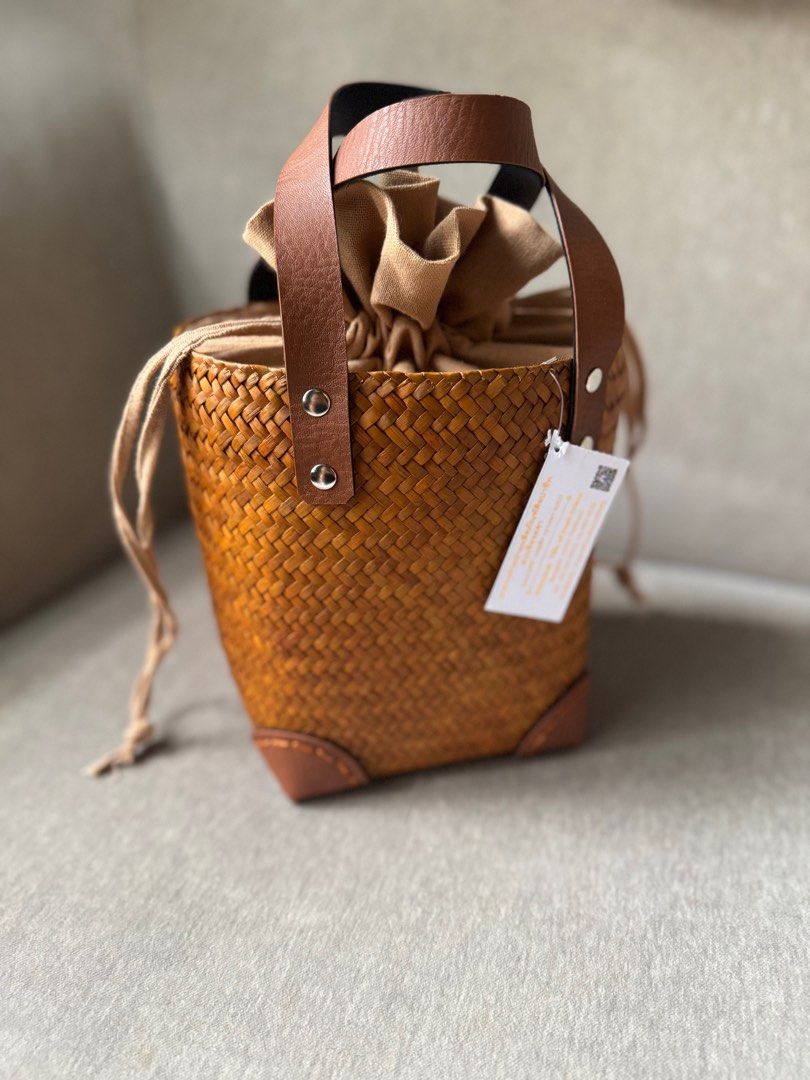 Woven Basket Bag with Leather Handles (Category: Tote Bags) located in Quezon City. Submitted by smt00 (Listing ID 1418227346, Image 2). Description: - Woven bucket bag - Brown leather handles and accents - Leather corner details - Made of natural woven material - Width: 6.5in Height: 7in - Bought in Bangkok .