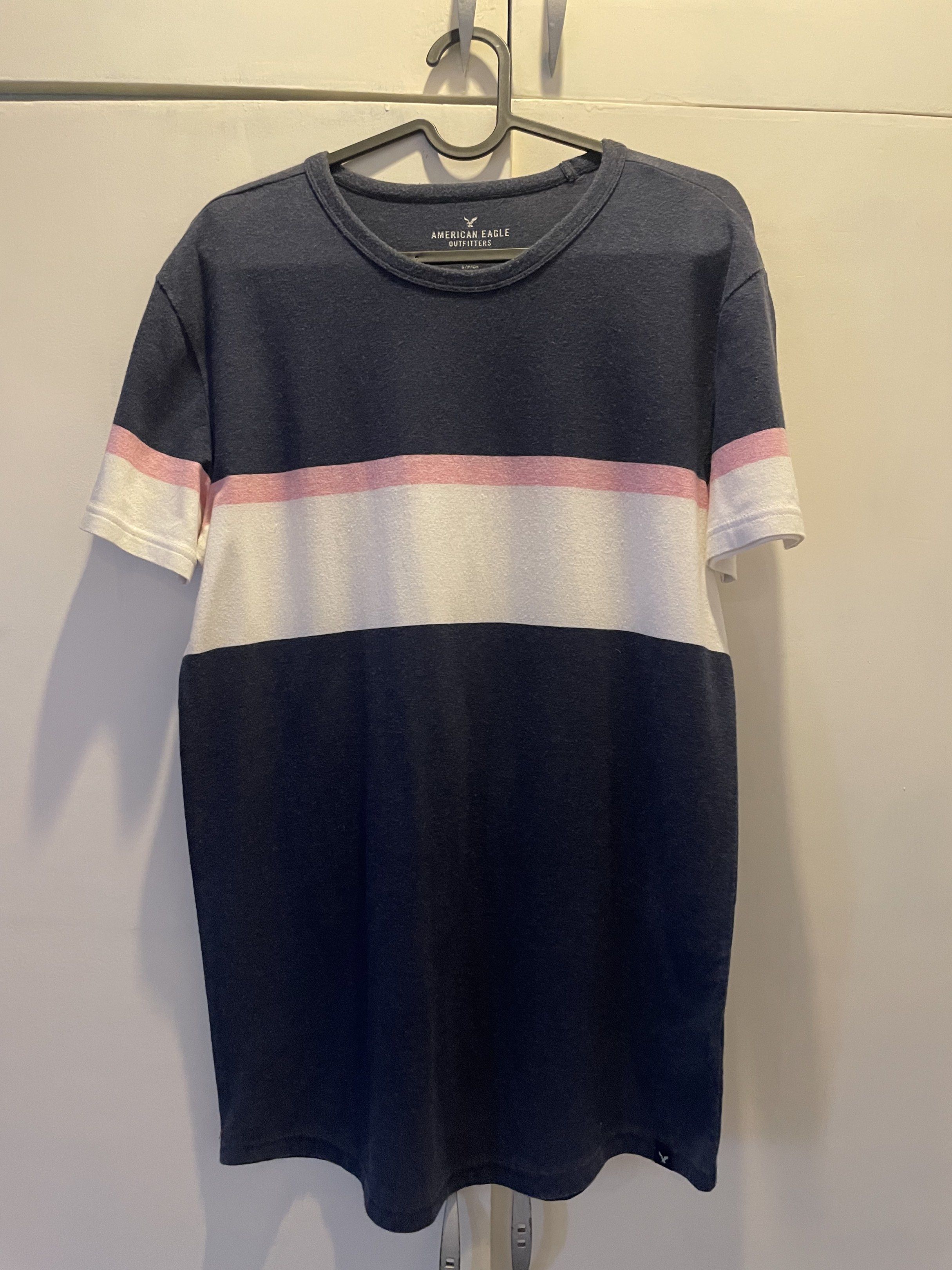 American Eagle Outfitters Active Flex T-shirt (Category: Tshirts & Polo Shirts ) located in Las Pinas. Submitted by bmtl_ (Listing ID 1418526315, Image 1). Description: American Eagle Outfitters Active Flex T-shirt. Features a navy blue base with pink and white horizontal stripes across the chest. Made in Vietnam. Size S/P/CH. The shirt has a crew neck and short sleeves..