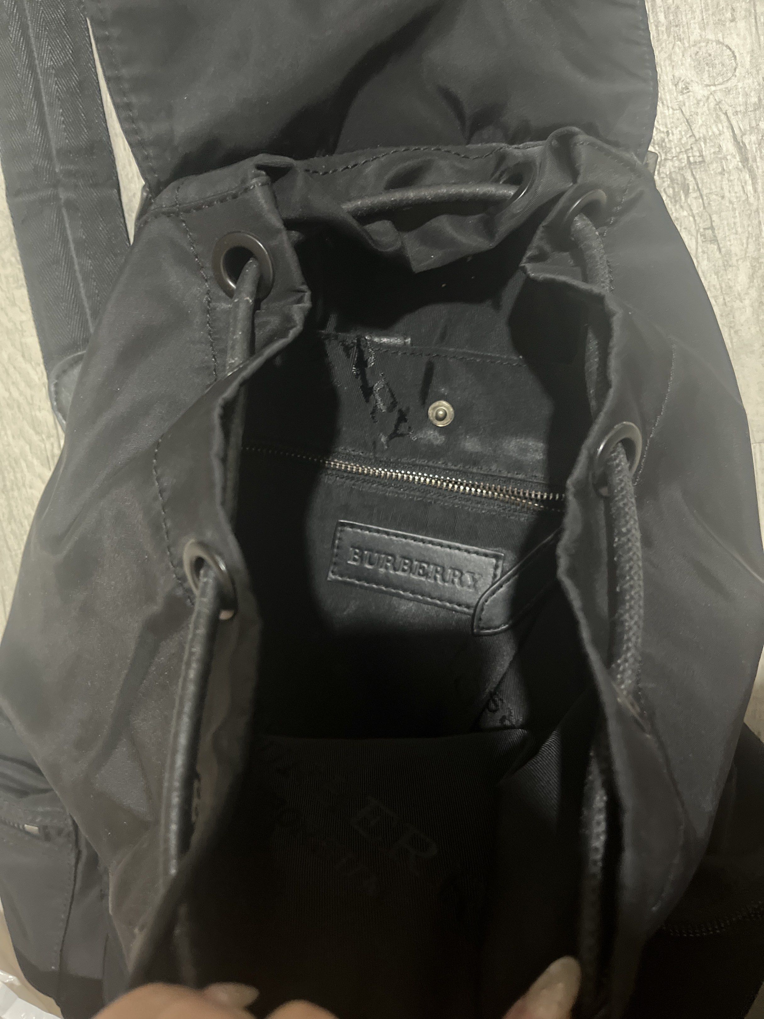 Original Burberry Black Backpack (Category: Luxury Bags & Wallets) located in Mandaluyong City. Submitted by lopezsam (Listing ID 1418543118, Image 2). Description: Features a drawstring closure, front pocket, and side pockets. The backpack has leather accents and adjustable straps. The interior has a Burberry label. The back of the backpack has a quilted design. Includes a top handle for carrying..