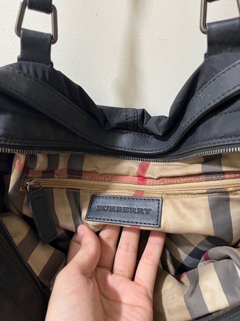 Burberry Black Tote Bag (Category: Luxury Bags & Wallets) located in Caloocan City. Submitted by pumarenluc79160 (Listing ID 1418555363, Image 3). Description: - Authentic Burberry tote bag - Classic black design - Drawstring closure on sides - Signature Burberry check interior lining - Includes an internal zipper pocket - Durable leather handles and trim - Burberry logo detailing on front and inside.