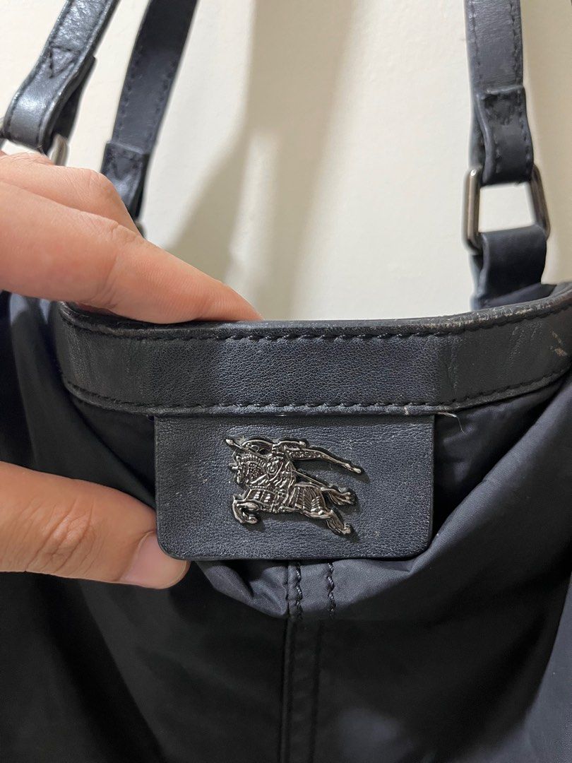 Burberry Black Tote Bag (Category: Luxury Bags & Wallets) located in Caloocan City. Submitted by pumarenluc79160 (Listing ID 1418555363, Image 2). Description: - Authentic Burberry tote bag - Classic black design - Drawstring closure on sides - Signature Burberry check interior lining - Includes an internal zipper pocket - Durable leather handles and trim - Burberry logo detailing on front and inside.