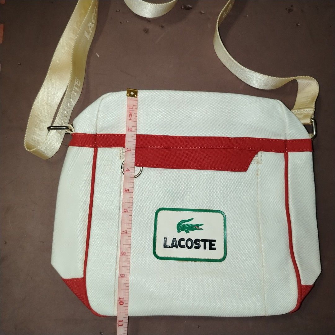 Lacoste White and Red Crossbody Bag (Category: Cross-body Bags) located in Manila. Submitted by d.ese_06 (Listing ID 1418449641, Image 3). Description: Negotiable Condition 8/10 Lightly Used Gcash payment Loc. Sampaloc manila Lacoste crossbody bag features a white body with red accents. It has a zippered main compartment and an adjustable shoulder strap. The interior lining is patterned with the Lacoste logo. The bag has a rectangular shape and a