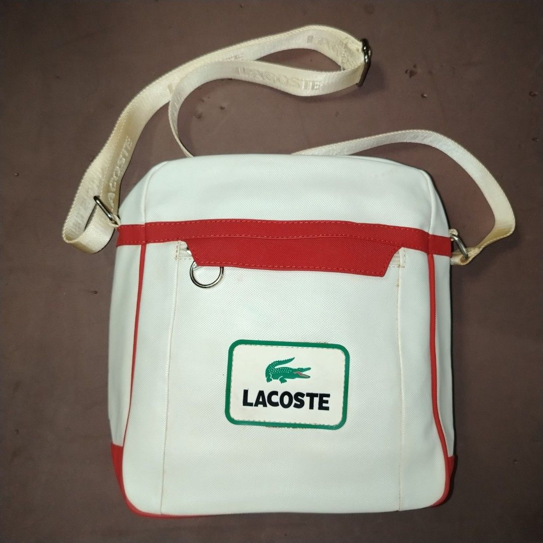 Lacoste White and Red Crossbody Bag (Category: Cross-body Bags) located in Manila. Submitted by d.ese_06 (Listing ID 1418449641, Image 1). Description: Negotiable Condition 8/10 Lightly Used Gcash payment Loc. Sampaloc manila Lacoste crossbody bag features a white body with red accents. It has a zippered main compartment and an adjustable shoulder strap. The interior lining is patterned with the Lacoste logo. The bag has a rectangular shape and a