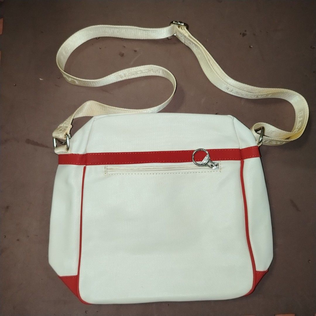 Lacoste White and Red Crossbody Bag (Category: Cross-body Bags) located in Manila. Submitted by d.ese_06 (Listing ID 1418449641, Image 2). Description: Negotiable Condition 8/10 Lightly Used Gcash payment Loc. Sampaloc manila Lacoste crossbody bag features a white body with red accents. It has a zippered main compartment and an adjustable shoulder strap. The interior lining is patterned with the Lacoste logo. The bag has a rectangular shape and a