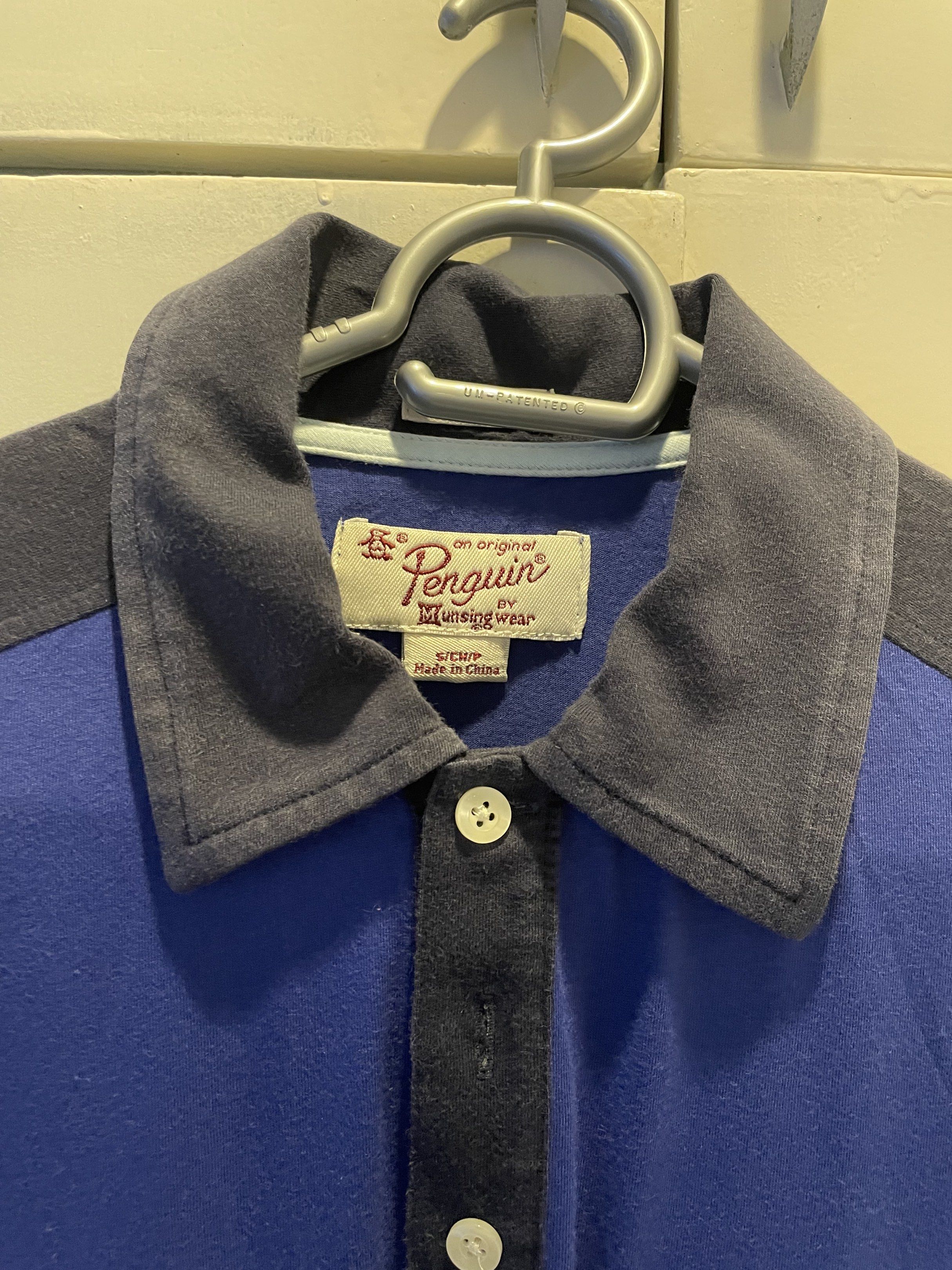 Original Penguin Polo Shirt (Category: Tshirts & Polo Shirts ) located in Las Pinas. Submitted by bmtl_ (Listing ID 1418526051, Image 2). Description: Original Penguin polo shirt in blue with a contrasting grey collar and shoulder panels. Features a pocket on the chest and the iconic Penguin logo embroidered on the bottom. The shirt has a button-up placket and a classic polo collar. Made by Munsingwear..