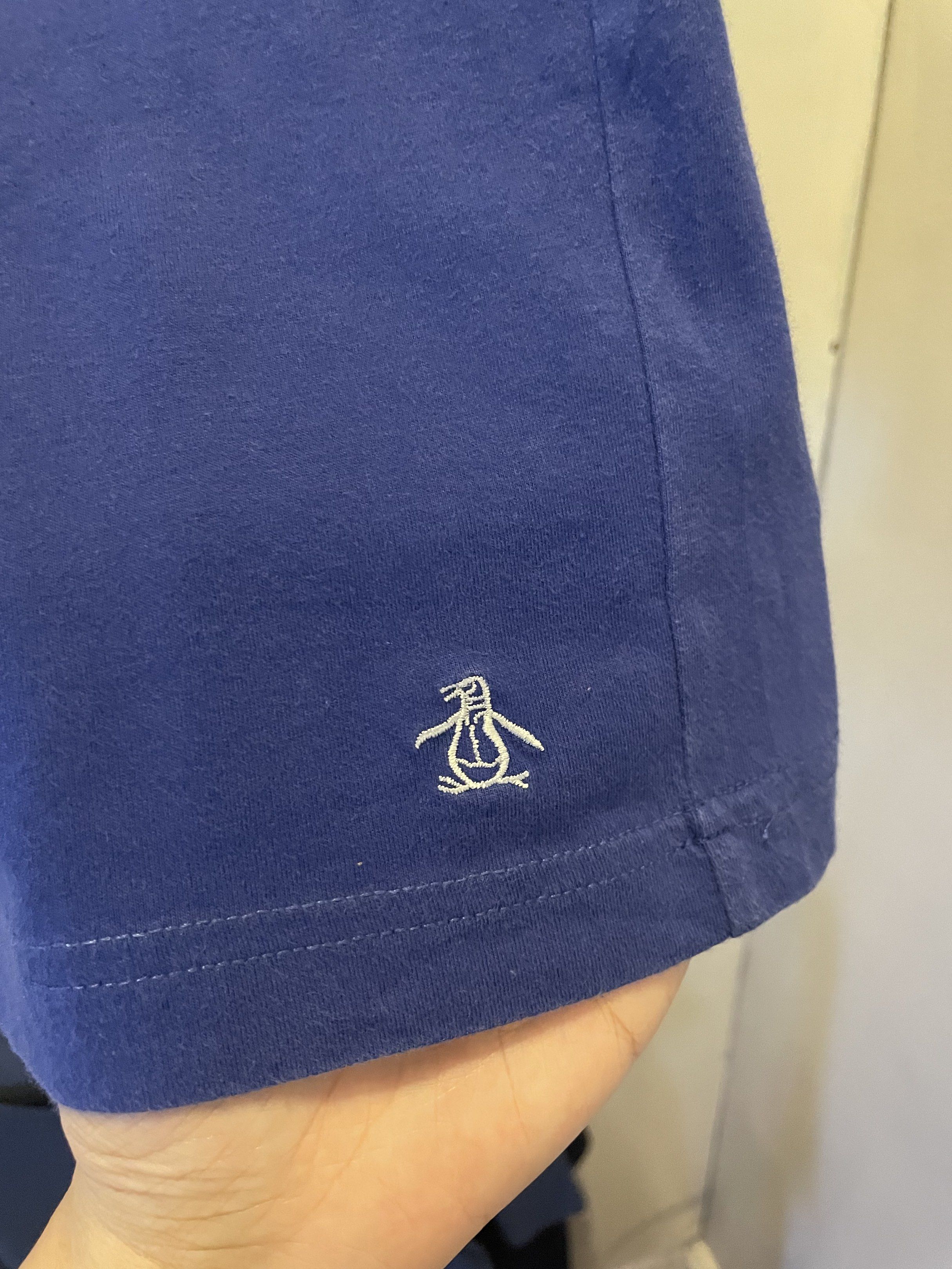 Original Penguin Polo Shirt (Category: Tshirts & Polo Shirts ) located in Las Pinas. Submitted by bmtl_ (Listing ID 1418526051, Image 3). Description: Original Penguin polo shirt in blue with a contrasting grey collar and shoulder panels. Features a pocket on the chest and the iconic Penguin logo embroidered on the bottom. The shirt has a button-up placket and a classic polo collar. Made by Munsingwear..