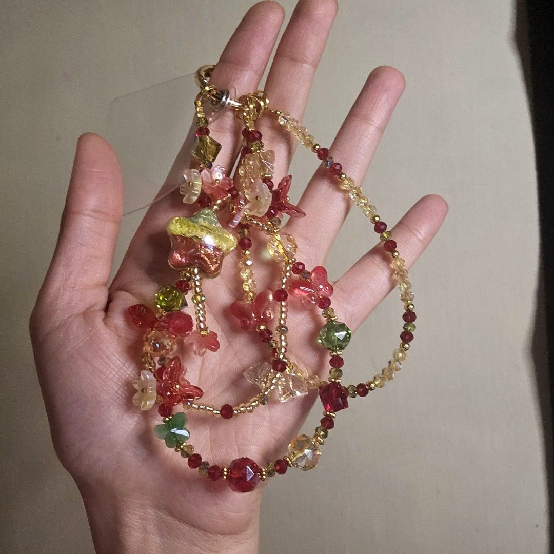 Red, Yellow, and Green Phone Charm (Category: Necklaces) located in Las Pinas. Submitted by klya00 (Listing ID 1418450746, Image 1). Description: - Colorful beaded phone charm - Features red, green, and yellow beads - Includes flower, star, and butterfly charms - Gold-colored chain - Lobster clasp closure - Handmade design - Perfect for adding a fun and whimsy touch to your outfit.