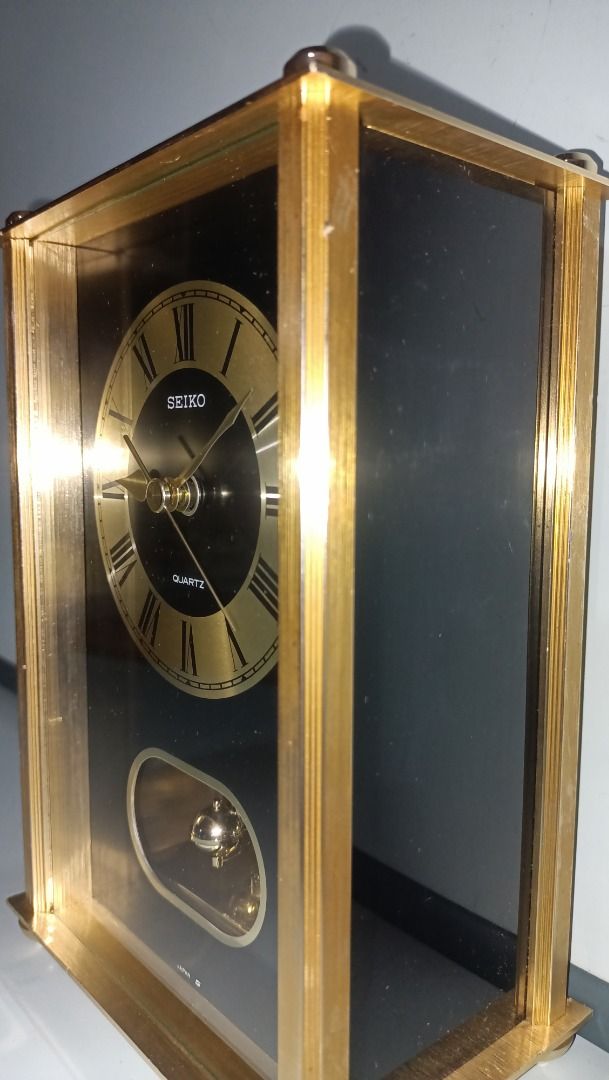 Seiko Quartz Pendulum Clock - Working (Category: Clocks) located in Munoz. Submitted by larryc1212 (Listing ID 1418566882, Image 3). Description: The clock is in working condition. Seiko quartz clock features a gold-toned frame and a black face with Roman numeral hour markers. The clock has a pendulum and is marked "Quartz" on the face. The movement is marked "Seiko", "10 Jewels", and "Japan". The back of the clock has Japanese writing and the da