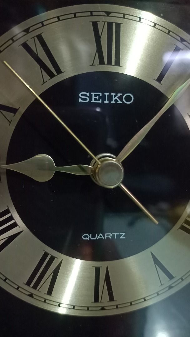 Seiko Quartz Pendulum Clock - Working (Category: Clocks) located in Munoz. Submitted by larryc1212 (Listing ID 1418566882, Image 2). Description: The clock is in working condition. Seiko quartz clock features a gold-toned frame and a black face with Roman numeral hour markers. The clock has a pendulum and is marked "Quartz" on the face. The movement is marked "Seiko", "10 Jewels", and "Japan". The back of the clock has Japanese writing and the da