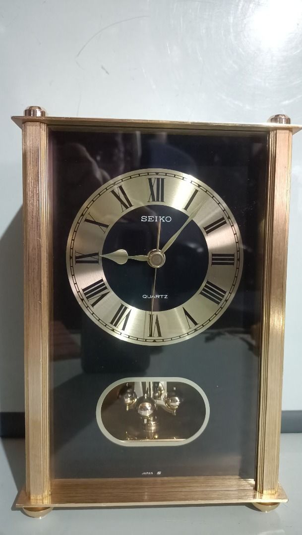 Seiko Quartz Pendulum Clock - Working (Category: Clocks) located in Munoz. Submitted by larryc1212 (Listing ID 1418566882, Image 1). Description: The clock is in working condition. Seiko quartz clock features a gold-toned frame and a black face with Roman numeral hour markers. The clock has a pendulum and is marked "Quartz" on the face. The movement is marked "Seiko", "10 Jewels", and "Japan". The back of the clock has Japanese writing and the da