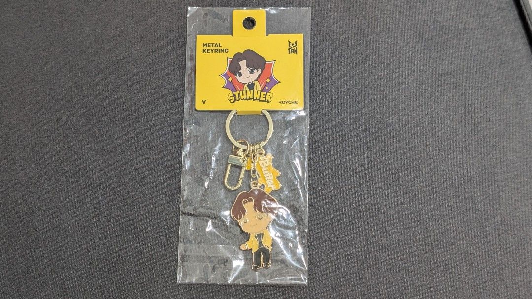 TinyTAN by BTS Metal Keyring / Royche Stunner (V) (Category: K-Wave Merchandise) located in Paranaque City. Submitted by coronelmafa (Listing ID 1418496846, Image 1). Description: Selling brand-new BTS V keychain. TinyTAN. Bought in Korea. - TinyTAN inspired metal keyring - Gold-colored design - Features BTS V - Includes a clasp - Brand new, still in original packaging .