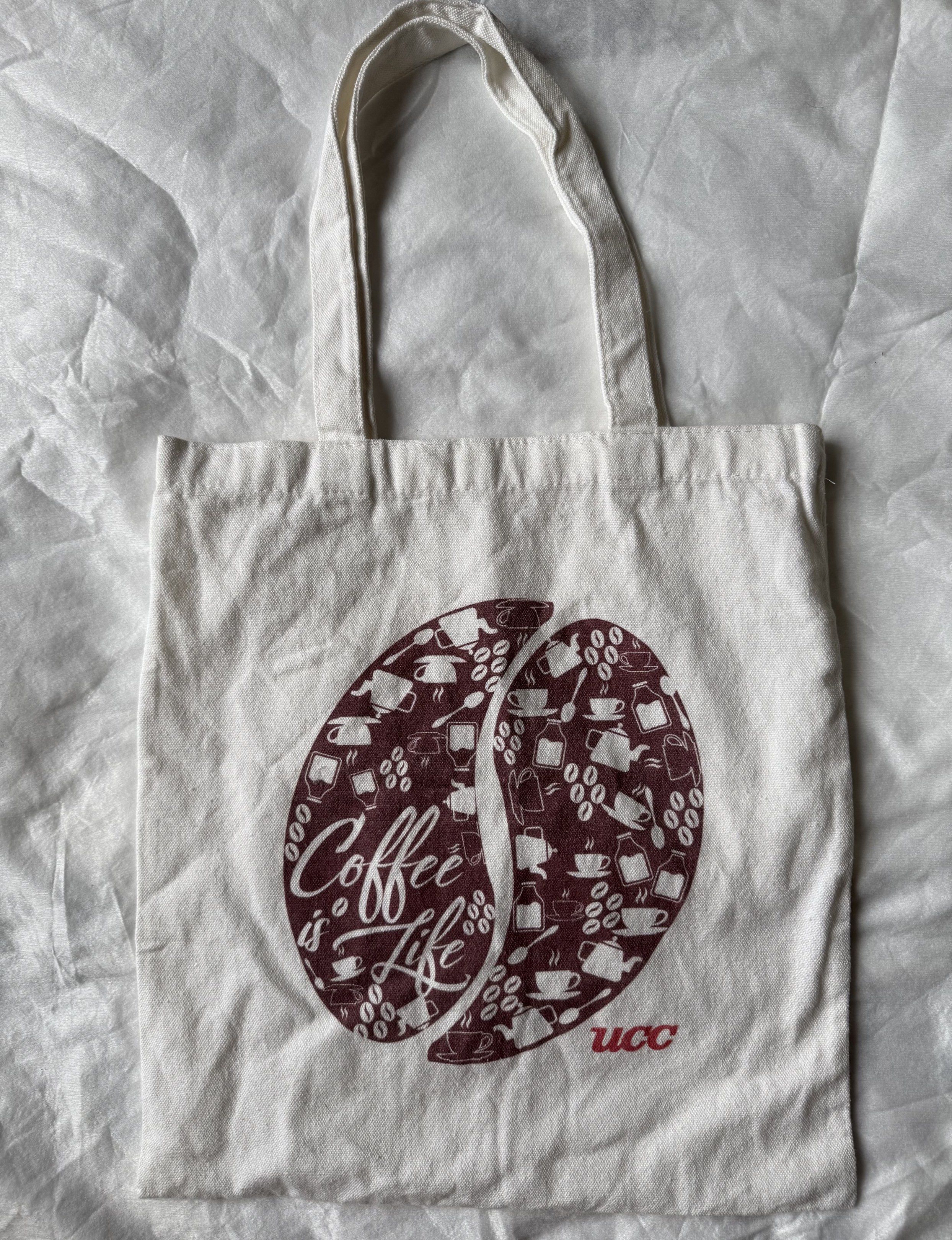 UCC Coffee Is Life Tote Bag (Category: Tote Bags) located in Manila. Submitted by stuffcartph (Listing ID 1418428689, Image 1). Description: RFS DECLUTTER - Coffee is Life tote bag - Features a white background - Maroon coffee bean graphic - Includes the UCC logo - Made of durable canvas material - Convenient two handles for carrying.