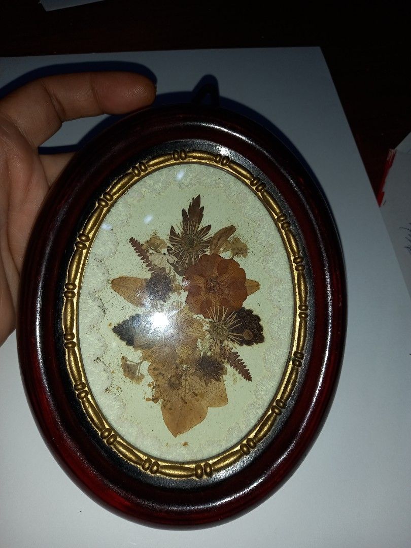 Vintage Pressed Flower Oval Frame (Category: Wall Decor) located in Manila. Submitted by zenphoenix-7ad615 (Listing ID 1418591894, Image 3). Description: - Vintage pressed flower wall decor - Oval frame with dark wood finish - Gold-colored trim - Features a beautiful floral arrangement - Includes a hook for easy hanging - Price tag on the back.