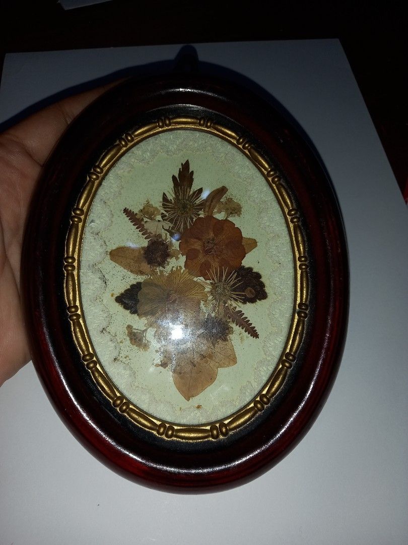 Vintage Pressed Flower Oval Frame (Category: Wall Decor) located in Manila. Submitted by zenphoenix-7ad615 (Listing ID 1418591894, Image 2). Description: - Vintage pressed flower wall decor - Oval frame with dark wood finish - Gold-colored trim - Features a beautiful floral arrangement - Includes a hook for easy hanging - Price tag on the back.