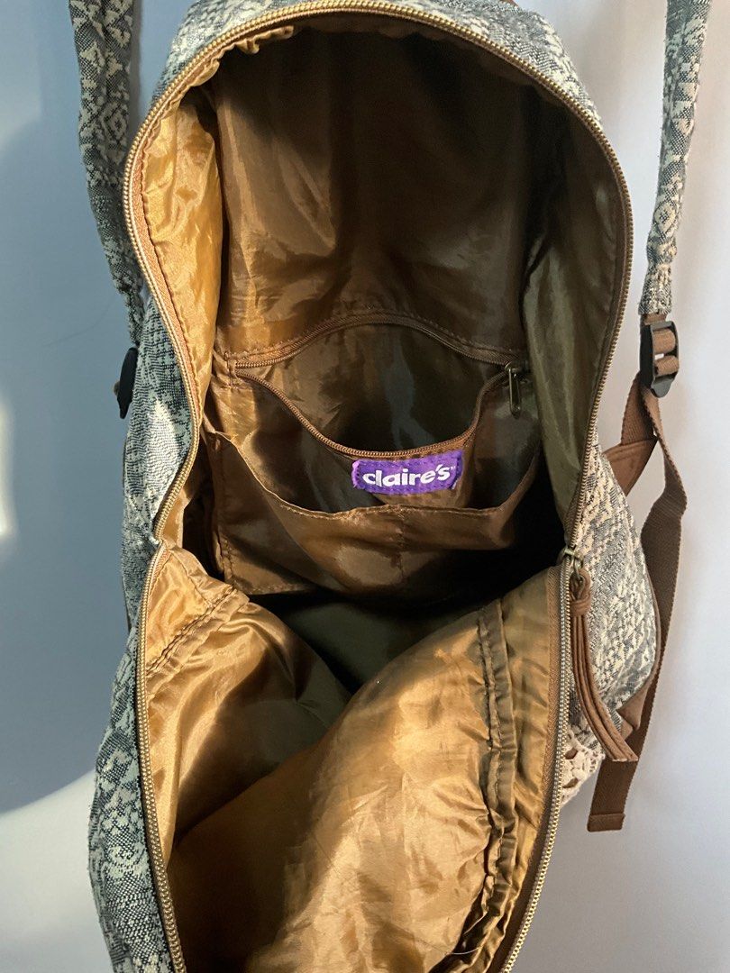 Claire's Patterned Backpack (Category: Backpacks) located in San Pedro. Submitted by dottable (Listing ID 1413434046, Image 2). Description: - Unique patterned design (reminiscent of 2010s) with lace detail - Adjustable straps and top handle - Multiple interior pockets - Includes a pocket with a Claire's label - Brown leather-like base and accents - Compact size, perfect for everyday use (13in in height).