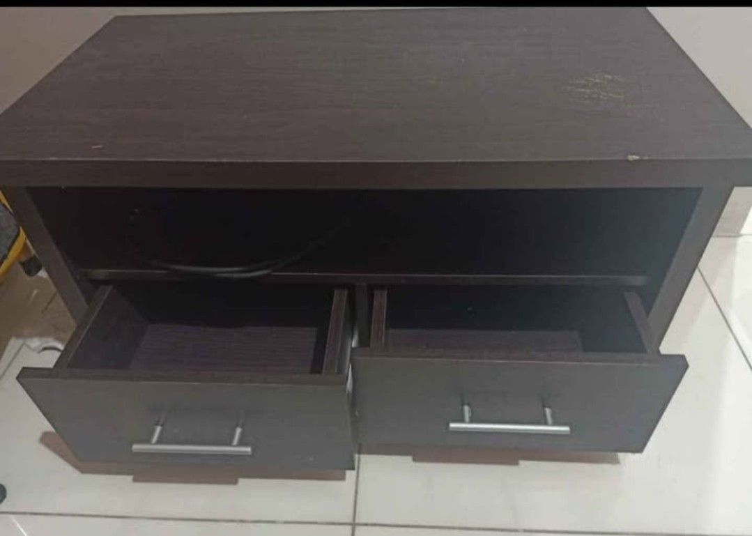Dark Brown TV Stand with Drawers (Category: TV Consoles) located in Quezon City. Submitted by cherry018 (Listing ID 1413394005, Image 1). Description: - Dark brown wooden TV stand - Two drawers with silver handles - Open shelf for storage - Rectangular shape - Ideal for TVs - Provides storage for media devices.