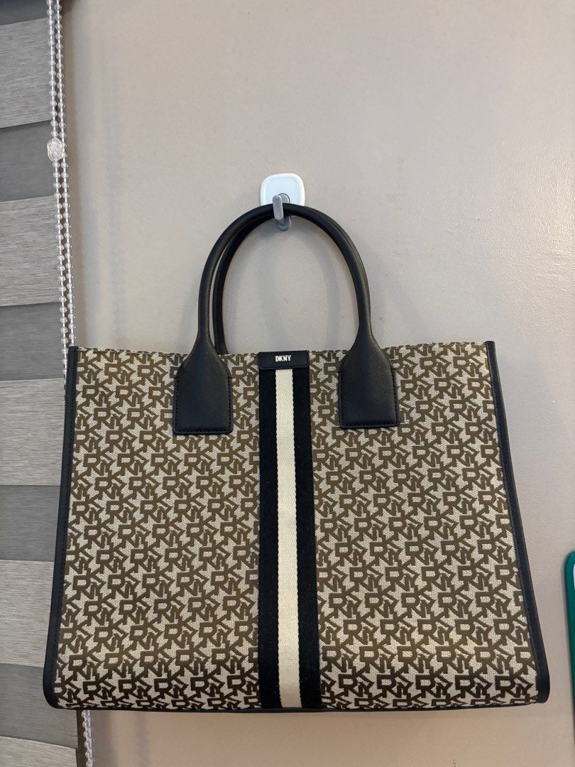 DKNY Tote Bag (Category: Luxury Bags & Wallets) located in Manila. Submitted by coolwinddd (Listing ID 1413384664, Image 1). Description: - DKNY tote bag - Monogram pattern - Black handles and trim - Vertical stripe detail - DKNY logo lining - Multiple compartments - Magnetic snap closure.
