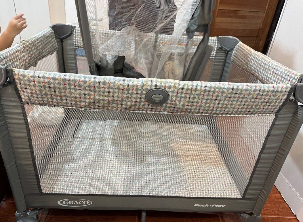 Graco Pack 'n Play Simple Solutions Playard (Category: Cots & Cribs) located in Manila. Submitted by theeditmarket (Listing ID 1413242319, Image 1). Description: - Graco Pack 'n Play Simple Solutions Playard - Features a removable full-size bassinet - Compact fold with automatically folding feet and wheels - Easy to store and travel-friendly - Includes a carrying bag - Stylish gray design with a patterned interior.