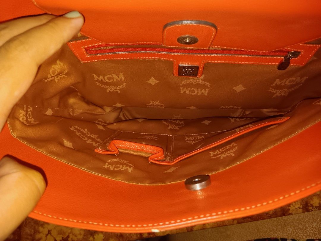 MCM Orange Tote Bag (Category: Luxury Bags & Wallets) located in Manila. Submitted by yumirayu (Listing ID 1413225780, Image 2). Description: - Color: Orange - Features double handles with silver hardware - Interior lined with MCM logo fabric - Includes a zippered pocket and additional compartments - Magnetic closure - Exterior shows some wear.