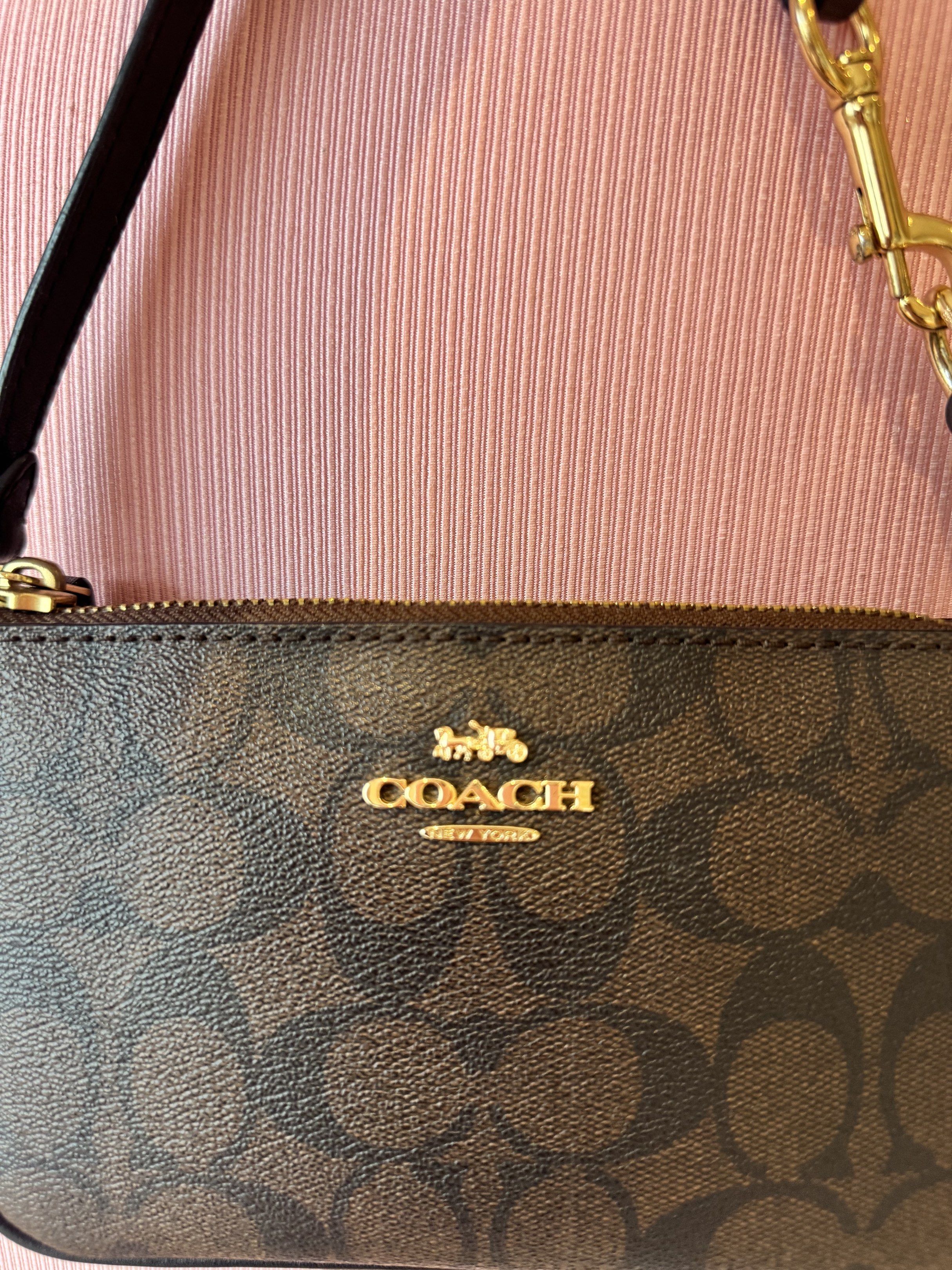 Coach Signature Wristlet (Category: Luxury Bags & Wallets) located in Cagayan de Oro. Submitted by declutteringszn (Listing ID 1418674400, Image 3). Description: - Authentic Coach wristlet - Signature brown Coach pattern - Top zipper closure - Detachable wrist strap - Gold-toned hardware - Compact design - Perfect for essentials.