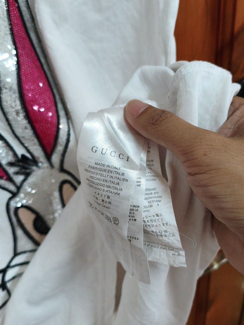 Gucci Bugs Bunny T-shirt (Category: Luxury Apparel) located in Tanay. Submitted by thrift_cy03 (Listing ID 1418755644, Image 3). Description: - Authentic Gucci T-shirt - Features a Bugs Bunny design with sequins - Made in Italy - Unique "GUCCY" design on the front - Size: W-19, L-28 - Classic round neck and short sleeves - Gucci logo visible on tag.