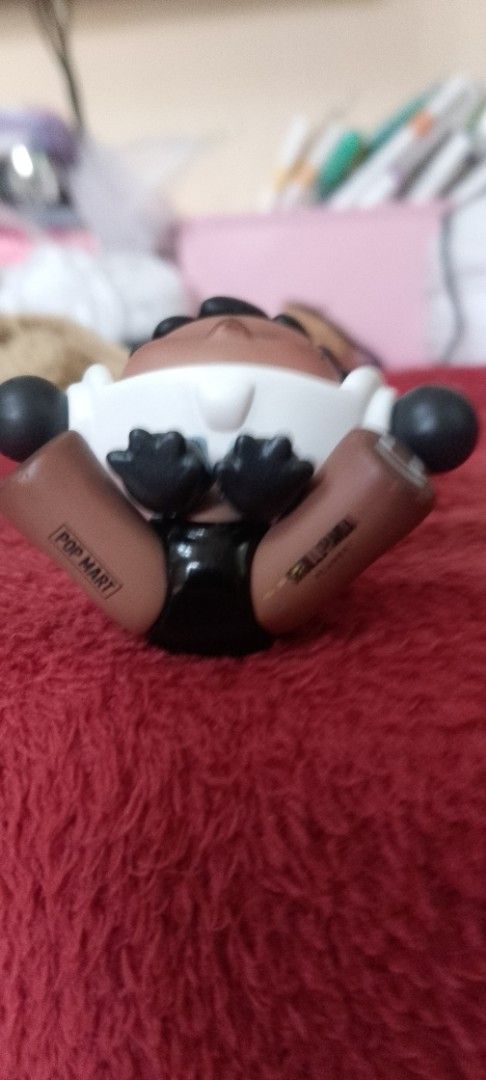 Pop Mart Skullpanda The Warmth Series Figure (Category: Designer & Blind Box Toys) located in Manila. Submitted by titojay (Listing ID 1418659069, Image 2). Description: Collectible figure features a unique design from the Pop Mart Skullpanda The Warmth Series. It has a distinctive appearance with a dark complexion, black hair, and a white headpiece. The figure is in a sitting position with a smiling face on one foot. The Pop Mart and Skullpanda 