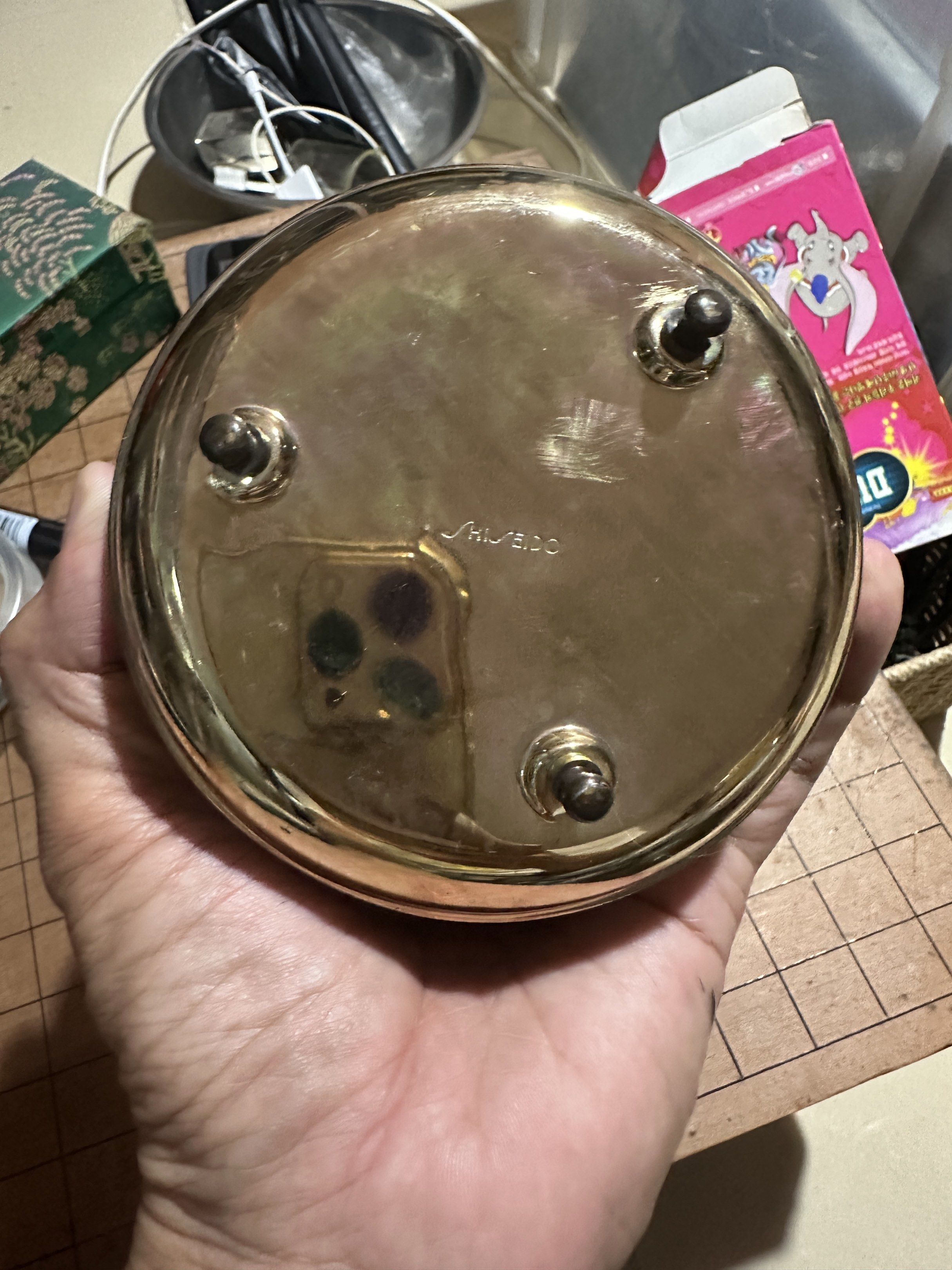 Shiseido Vintage Powder Compact (Category: Makeup) located in Rodriguez. Submitted by pwestoonlinestore (Listing ID 1418690960, Image 2). Description: - Vintage Shiseido powder compact - Ornate, gold-toned lid design - Features a central floral motif - Light yellow interior - Includes a small handle - Base has three small feet.