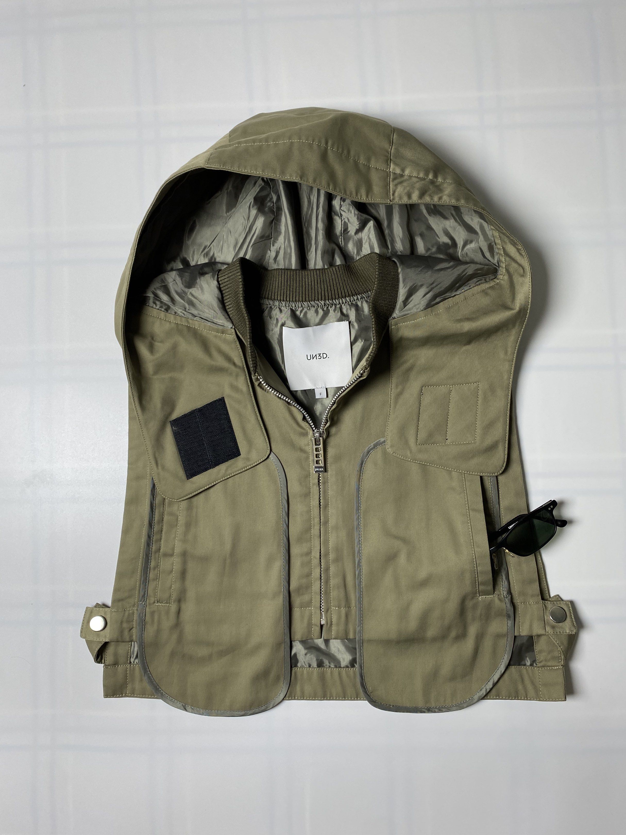AW21 UN3D HOODED VEST (Category: Coats, Jackets and Outerwear) located in Balanga. Submitted by faded_garmz (Listing ID 1418906409, Image 3). Description: AW21 UN3D HOODED VEST UN3D (UN-THREED) is a Japanese designer fashion brand founded in 2016 by creative director Momoko Ogihara. A military-inspired design with a hood and large, rounded front pockets. The short length is designed to create a balanced silhouette and can have a style-enhancing e