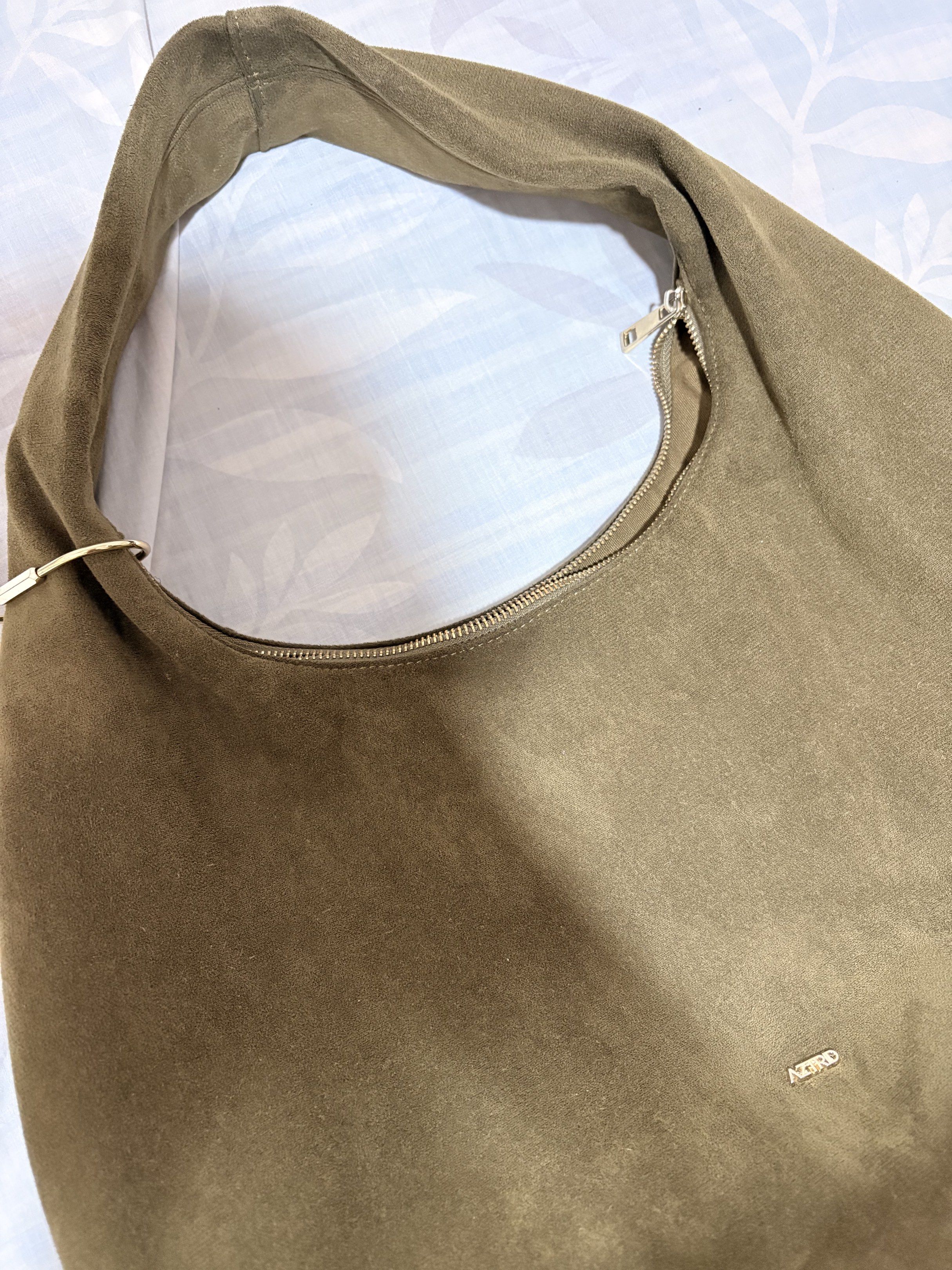 AZTRID Suede Hobo Bag Large (Suede Moss) (Category: Luxury Bags & Wallets) located in Manila. Submitted by tamia444_ (Listing ID 1418814722, Image 2). Description: Inclusions: Gold Charm Holder Dust Bag - Stylish AZTRD hobo bag - Color: Muted olive green - Features a single shoulder strap - Secure zippered closure - Spacious interior with an additional zippered pocket - Made of a soft, suede-like material - Minimalist design with subtle AZTRD log