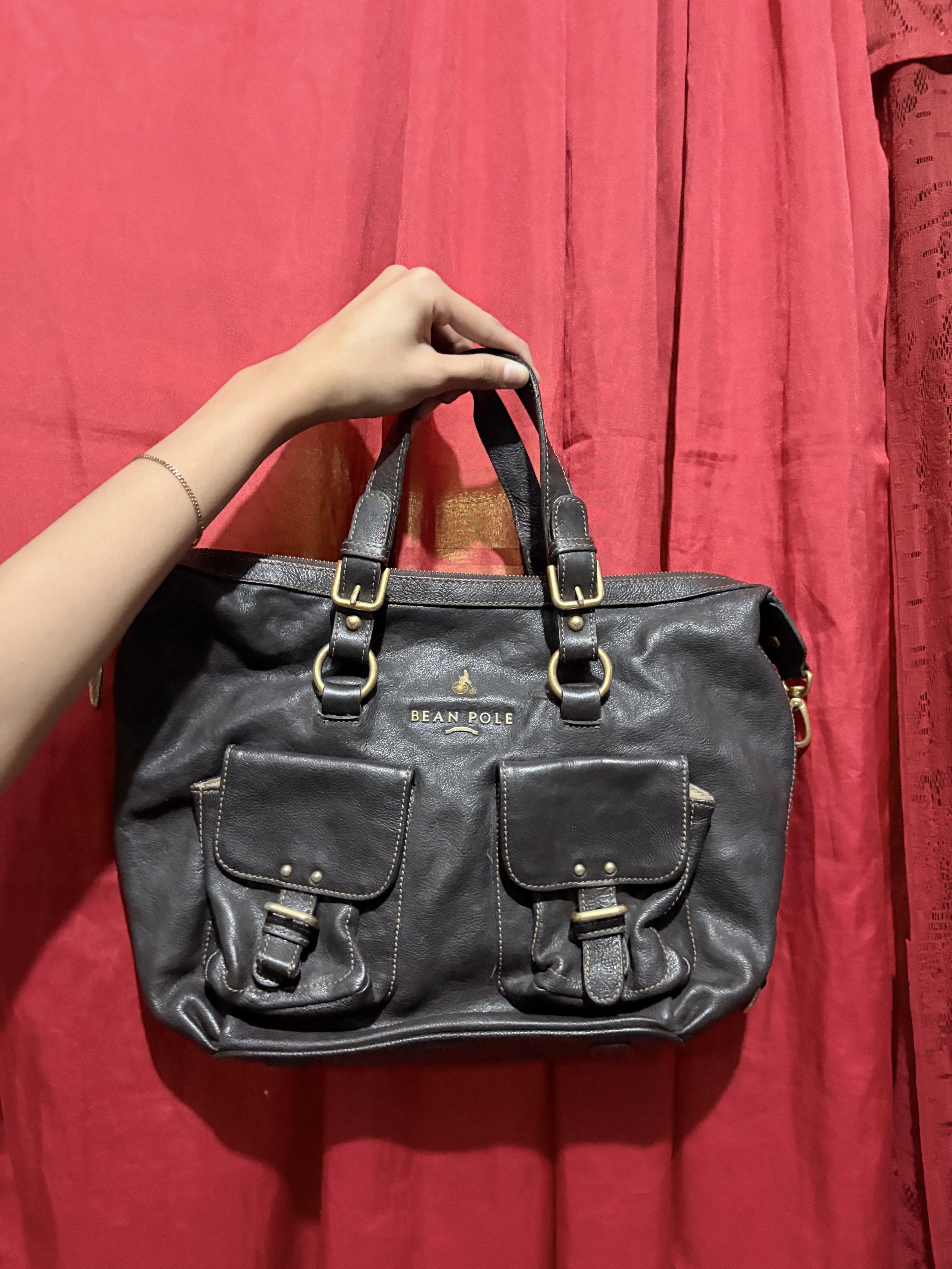 Bean Pole Leather Handbag (Category: Luxury Bags & Wallets) located in Manila. Submitted by cufflej (Listing ID 1418958235, Image 1). Description: - Brand: Bean Pole - Color: Dark Brown - Material: Leather - Features: - Two front pockets with buckle closures - Zippered back pocket - Two top handles - Gold-colored hardware - Light-colored interior lining - Includes: Detachable strap.