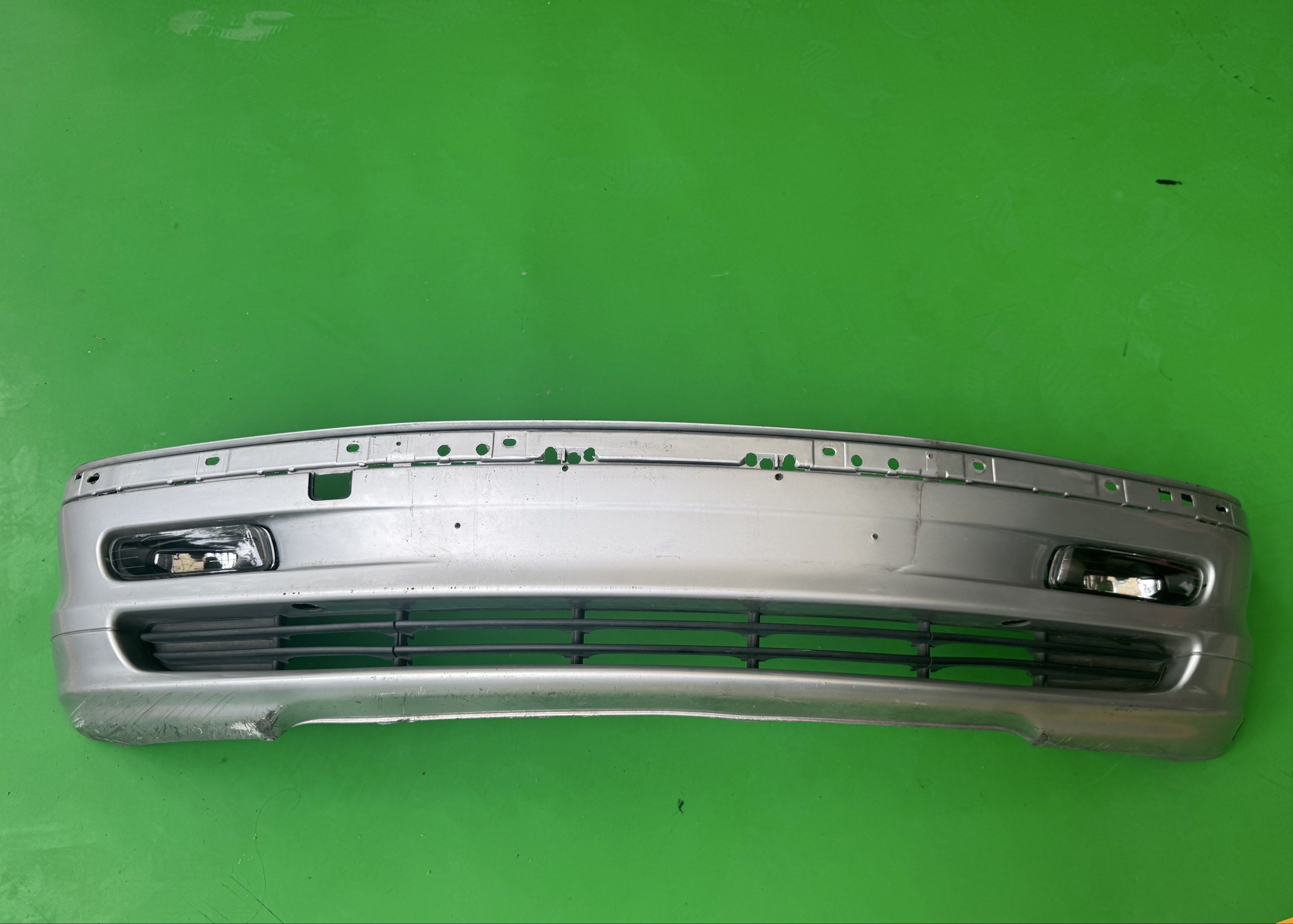 BMW E46 Prefacelift Silver Car Bumper with Fog Lights (Category: Body Parts and Accessories) located in Pasig City. Submitted by mp39393 (Listing ID 1418859659, Image 2). Description: - Silver car bumper with fog lights - Includes lower grille and mounting points - Designed for a specific car model, pre facelift E46 - Functional, despite some wear and tear.