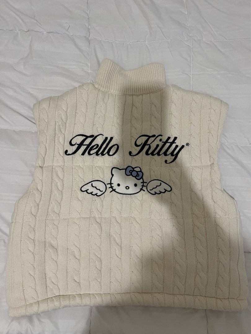 Forever 21 Hello Kitty Winter Knit Vest (Category: Others Tops) located in Manila. Submitted by clothingrack_ (Listing ID 1418882131, Image 2). Description: - Cream-colored cable knit vest - Features a Kitty design - High collar - Full zipper closure - Two front pockets - Kitty bow patch on the front - Kitty graphic with " Kitty" text on the back - Drawstring at the bottom hem.