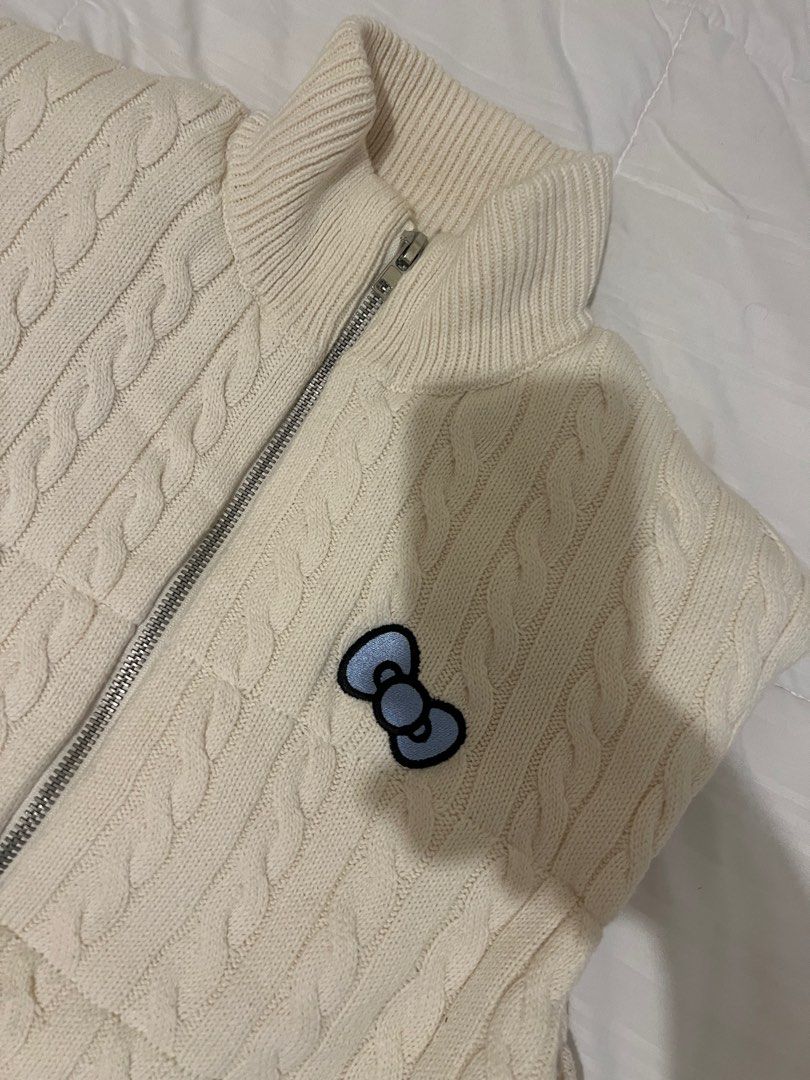 Forever 21 Hello Kitty Winter Knit Vest (Category: Others Tops) located in Manila. Submitted by clothingrack_ (Listing ID 1418882131, Image 3). Description: - Cream-colored cable knit vest - Features a Kitty design - High collar - Full zipper closure - Two front pockets - Kitty bow patch on the front - Kitty graphic with " Kitty" text on the back - Drawstring at the bottom hem.