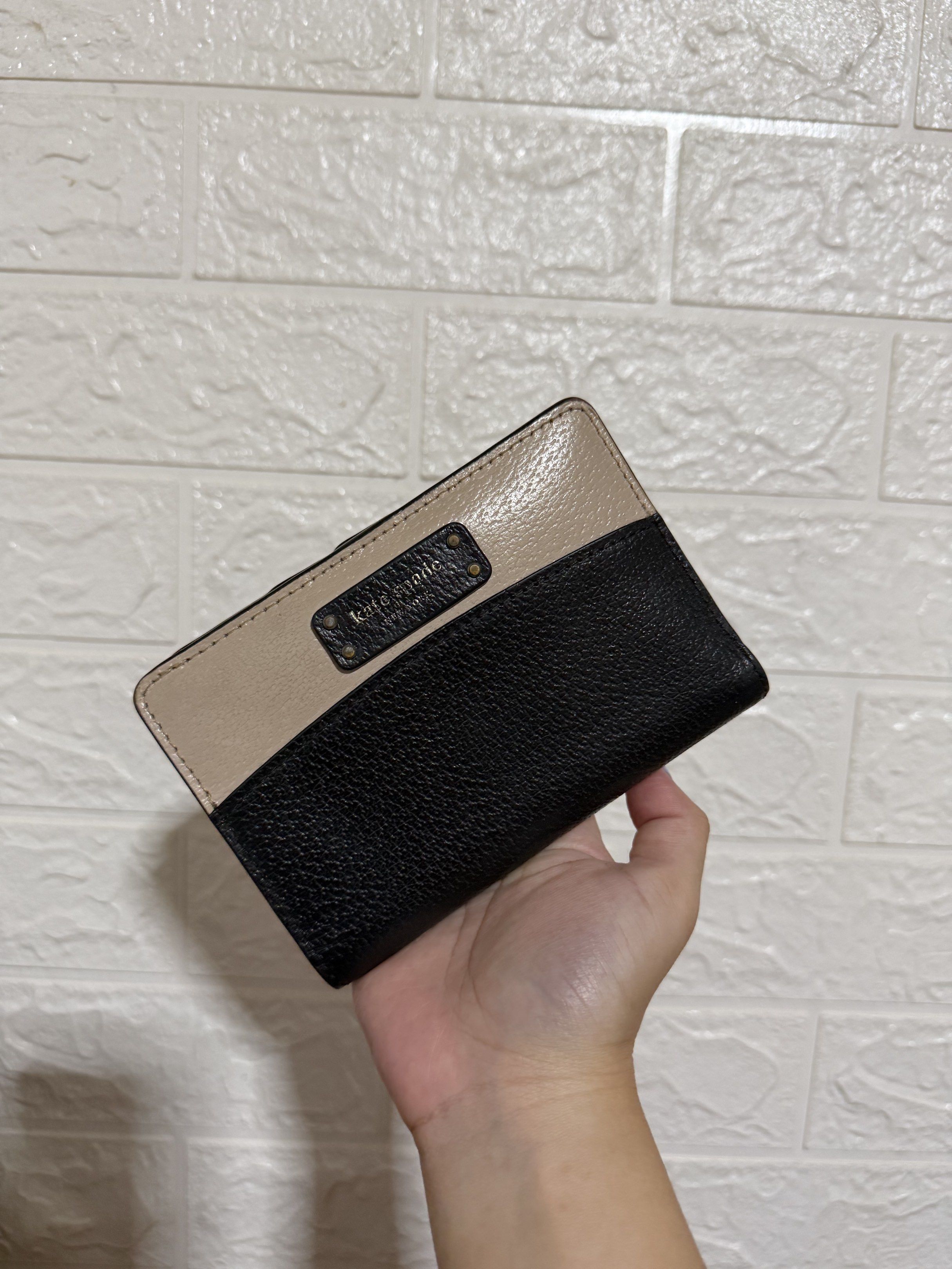 Kate Spade Bifold Wallet (Category: Wallets & Card holders) located in Las Pinas. Submitted by decluttxrstudios (Listing ID 1418797330, Image 1). Description: - Kate Spade bifold wallet - Color block design: black and beige leather - Features: - Zip-around closure (back) - Snap closure (front) - Kate Spade logo on the front - Compact size, ideal for daily use.