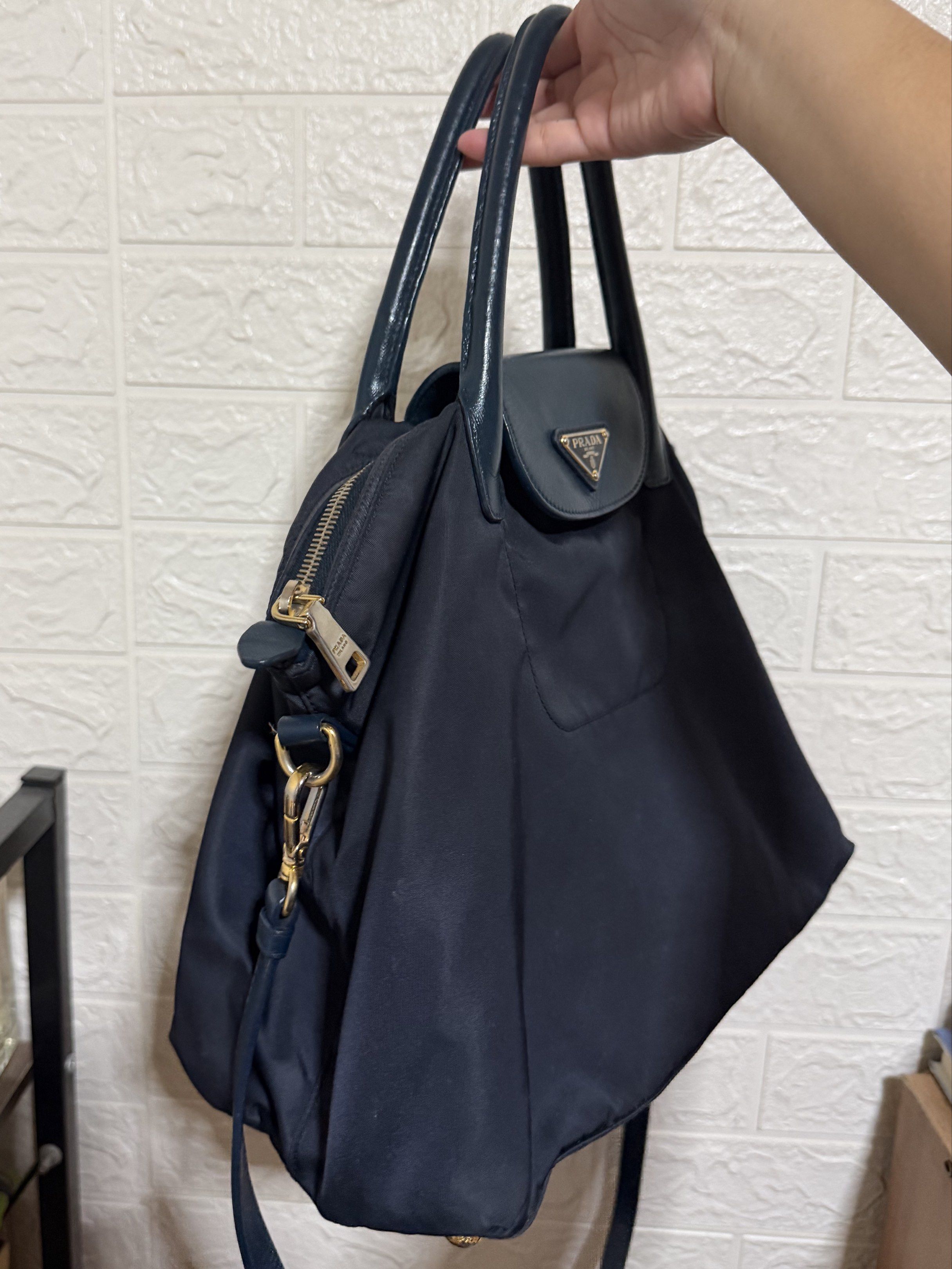 Prada Nylon Tessuto (Category: Luxury Bags & Wallets) located in Las Pinas. Submitted by decluttxrstudios (Listing ID 1418798133, Image 2). Description: - Color: Navy blue - Material: Nylon - Trim: Leather - Hardware: Gold-tone - Features a top handle and detachable shoulder strap - Closure: Zip - Includes a front pocket - Prada logo on the front Please self-authenticate, sold as is .