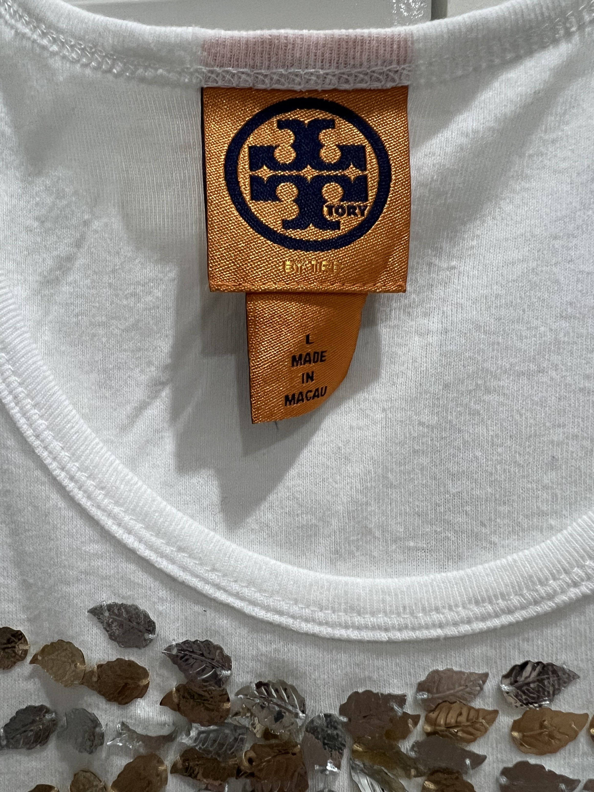 Tory Burch Embellished Tank Top - Size L (Category: Sleeveless) located in Cainta. Submitted by cendzz (Listing ID 1418876480, Image 2). Description: - Tory Burch tank top - White color - M built - Scoop neck, sleeveless design - Leaf-shaped embellishments - Sunburst pattern on chest - Soft, comfortable material.