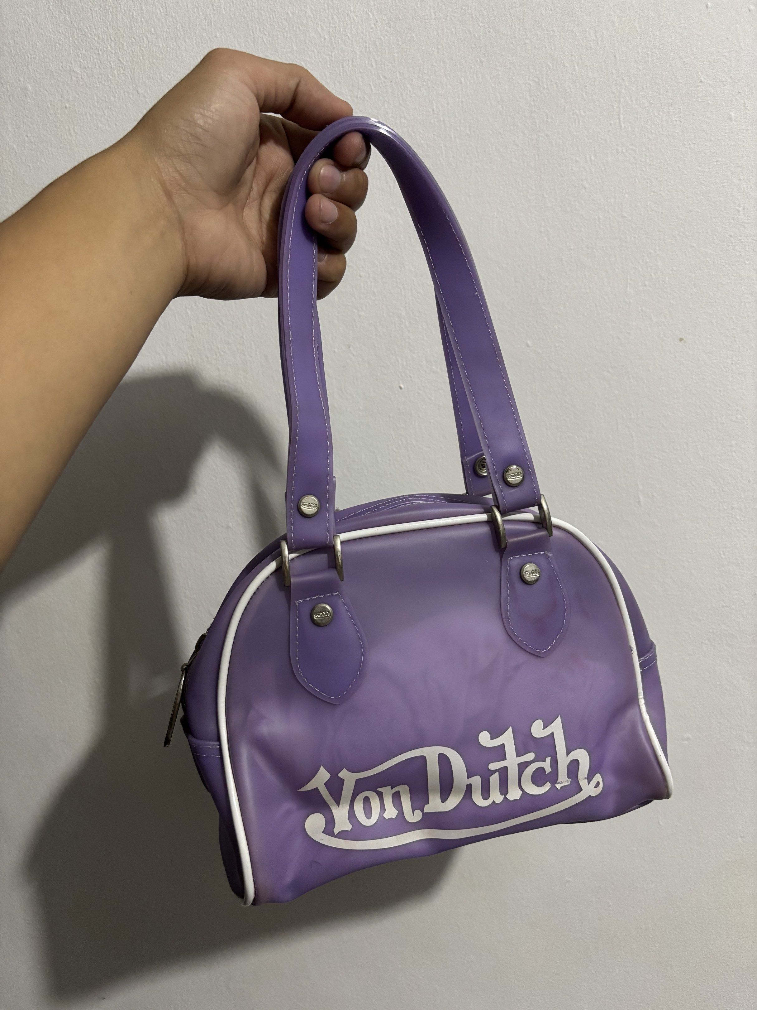 Von Dutch Purple Handbag (Category: Luxury Bags & Wallets) located in Manila. Submitted by kenriegab (Listing ID 1418814423, Image 1). Description: - Purple Von Dutch handbag - White trim - Top zipper closure - Dual top handles - White interior with zippered pocket - Von Dutch logo visible - Shows wear and tear.