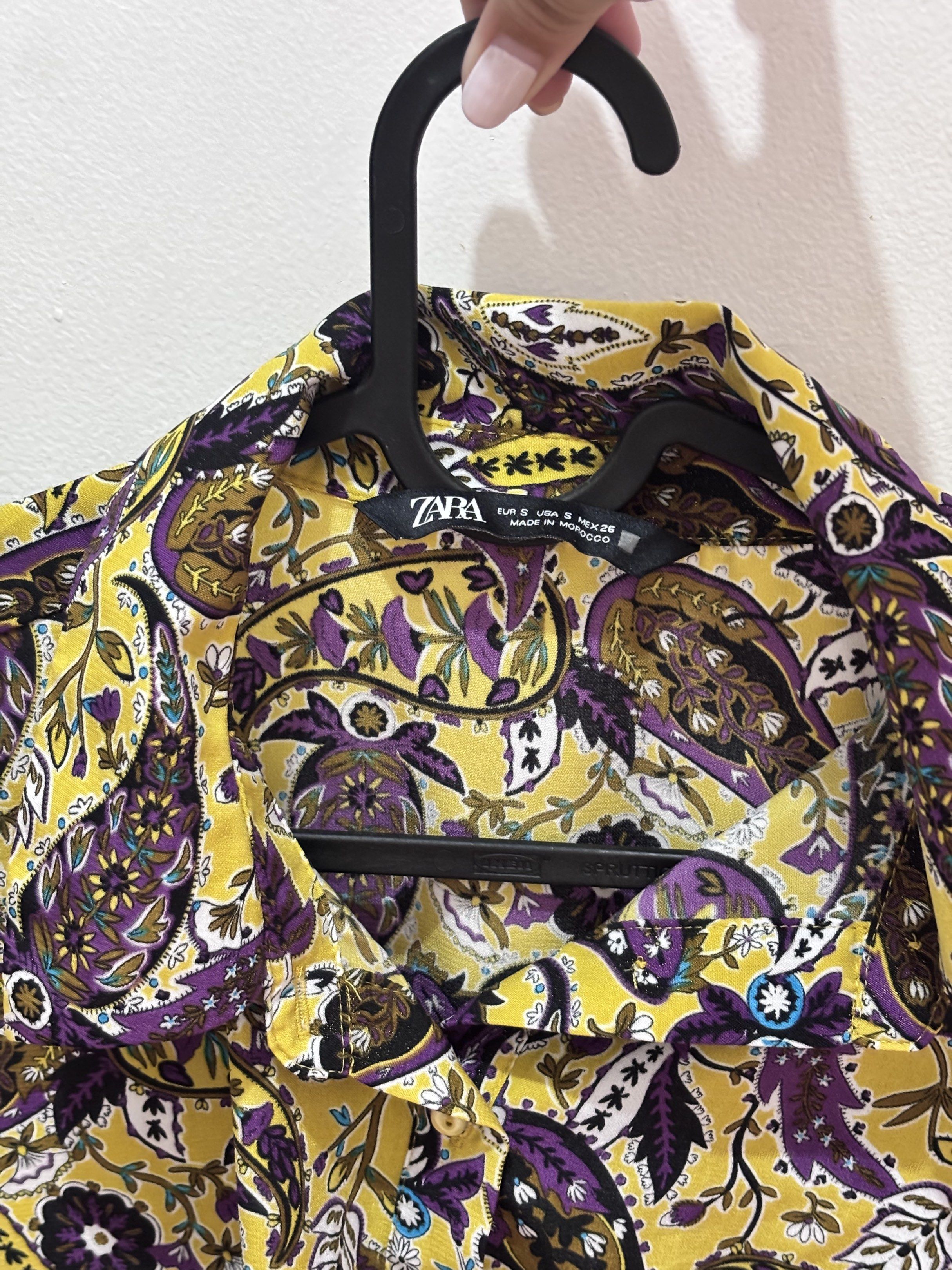 Zara Paisley Print Cropped Blouse (Category: Blouses) located in Meycauayan. Submitted by declutter0403 (Listing ID 1418817159, Image 2). Description: - Zara paisley blouse - Vibrant yellow and purple print - Cropped, knotted style - Size S - Long sleeves - Collared neckline - Button-down closure - Elastic hem at the back.