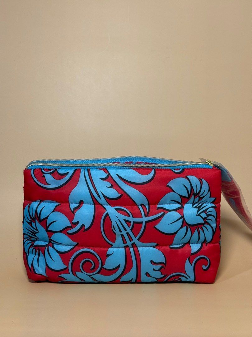 Estee Lauder Make Up Pouch (Category: Clutches) located in Pasig City. Submitted by chikaching (Listing ID 1413437034, Image 1). Description: Estee Lauder make up pouch features a vibrant red exterior with a blue floral design. The interior is lined with a light blue fabric and a repeating red text pattern. It has a zipper closure and a wrist strap. Slightly negotiable.