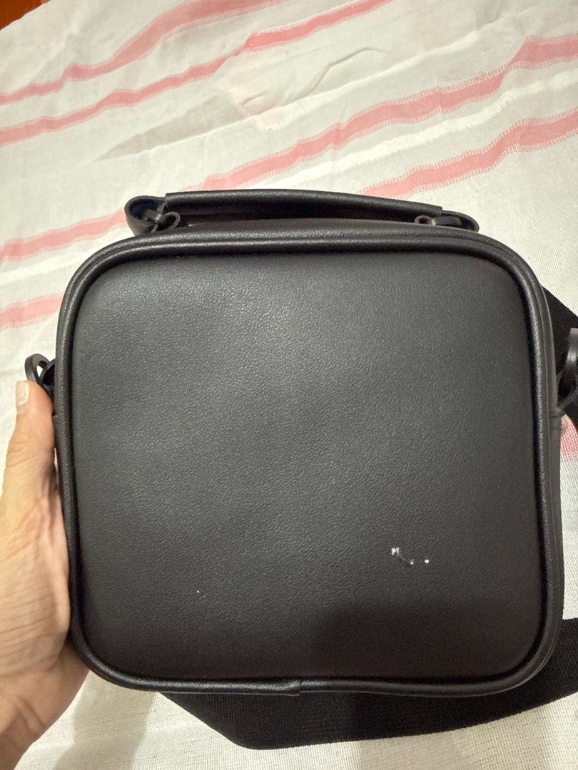 Free Smart Friday Crossbody Bag (Category: Sling Bags) located in Pasig City. Submitted by clouddansahh14 (Listing ID 1413580632, Image 2). Description: - Free Smart Friday crossbody bag - Square shape - Top handle and adjustable shoulder strap - Zippered main compartment - Brand name visible on front - Made of smooth, leather-like material .