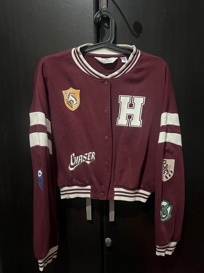 H&M Harry Potter Varsity Jacket (Category: Babies & Kids Fashion) located in San Mateo. Submitted by junked (Listing ID 1413616495, Image 1). Description: Maroon H&M varsity jacket with Harry Potter patches. Features white stripes on the sleeves and a "07" on the back. The jacket has a cropped fit and a button-up front. Size is EUR 146/152, US 12/14, CA 10-12A, CN 150/76, MX 10-12A, AUS 11-12, UK 10-12Y. Some wear and tear is visible on the sleev