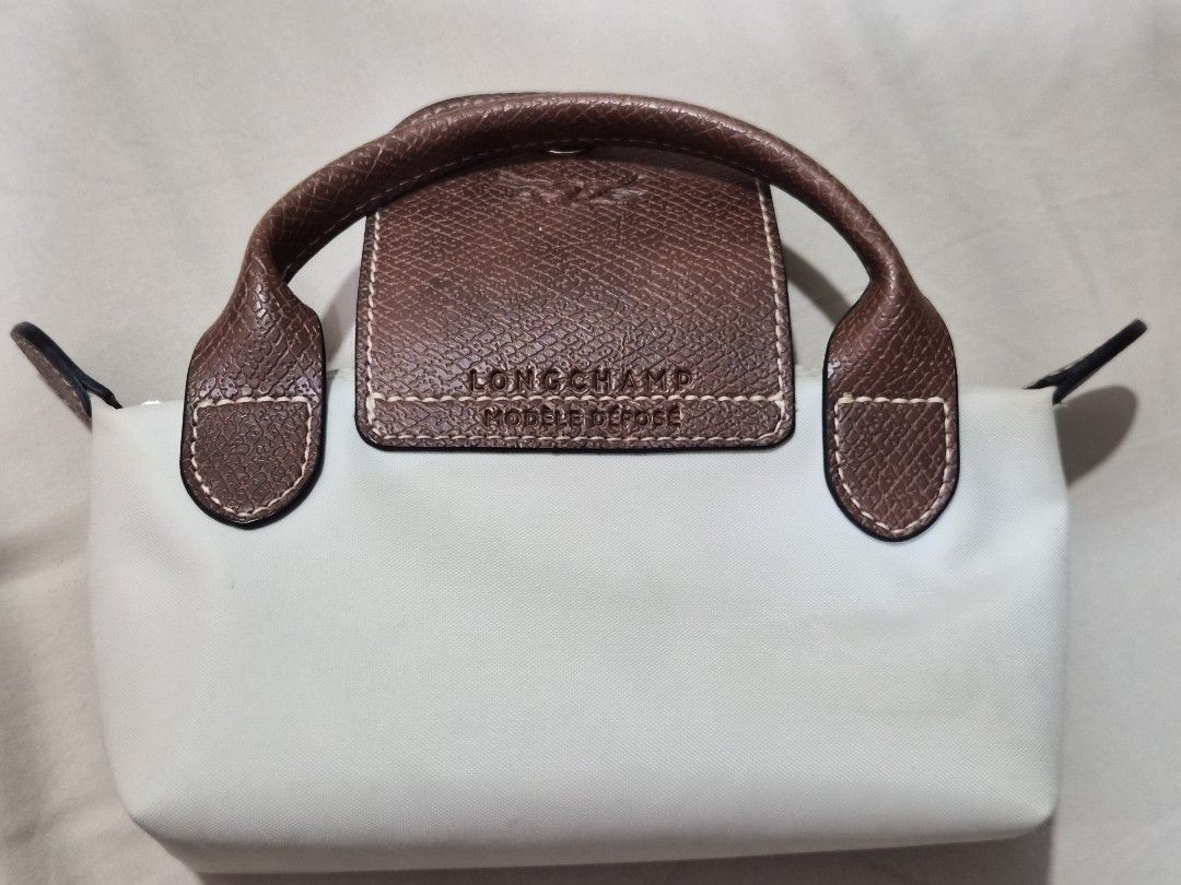 Longchamp Le Pliage Pouch (Category: Luxury Bags & Wallets) located in Muntinlupa City. Submitted by hcasi (Listing ID 1413539428, Image 2). Description: - Authentic Longchamp Le Pliage Pouch with Handle - Color: Paper - With signs of use as seen in photo (may still be cleaned) - Come with generic strap, bag organizer and bag charm - Bough from preloved online store (Shop Sonier) MOP: GCash/Maya/BPI MOD: Grab/Lalamove/J&T/LBC.