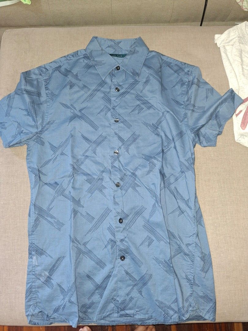 Perry Ellis Short Sleeve Shirt (Category: Tshirts & Polo Shirts ) located in Muntinlupa City. Submitted by eiramceegee (Listing ID 1413525350, Image 1). Description: Blue short sleeve shirt from Perry Ellis. Features a button-down front and a unique pattern. The shirt has a collar and short sleeves. The size is indicated as S. Made from a lightweight fabric, suitable for casual wear. Perfect for everyday use..