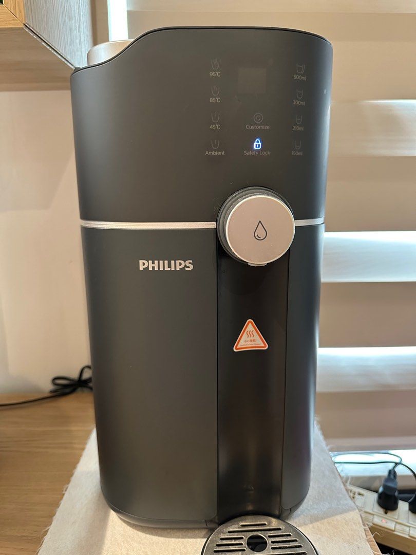 Philips Instant Water Dispenser (Category: Water Purifiers & Dispensers) located in Valenzuela. Submitted by jaylight (Listing ID 1413580364, Image 1). Description: RFS: Decluttering Philips instant water dispenser offers various temperature settings: 95°C, 85°C, 45°C, and ambient. It also has options for 500ml, 200ml, and 100ml dispensing, along with a customize feature. Features a safety lock for added security. The dispenser is dark gray in co